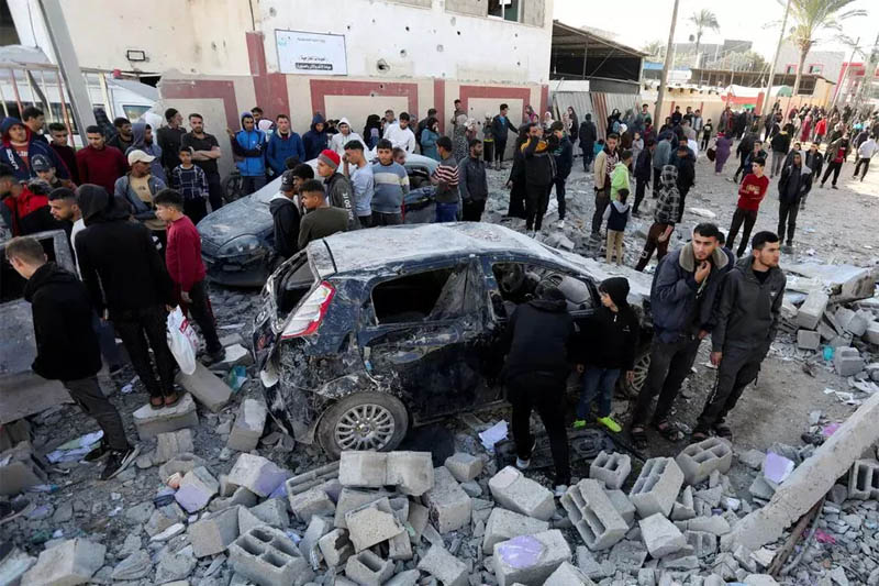 Warga Palestina berkumpul di samping kendaraan yang rusak saat mereka memeriksa lokasi serangan Israel, di Deir Al-Balah di Jalur Gaza tengah (10/1).