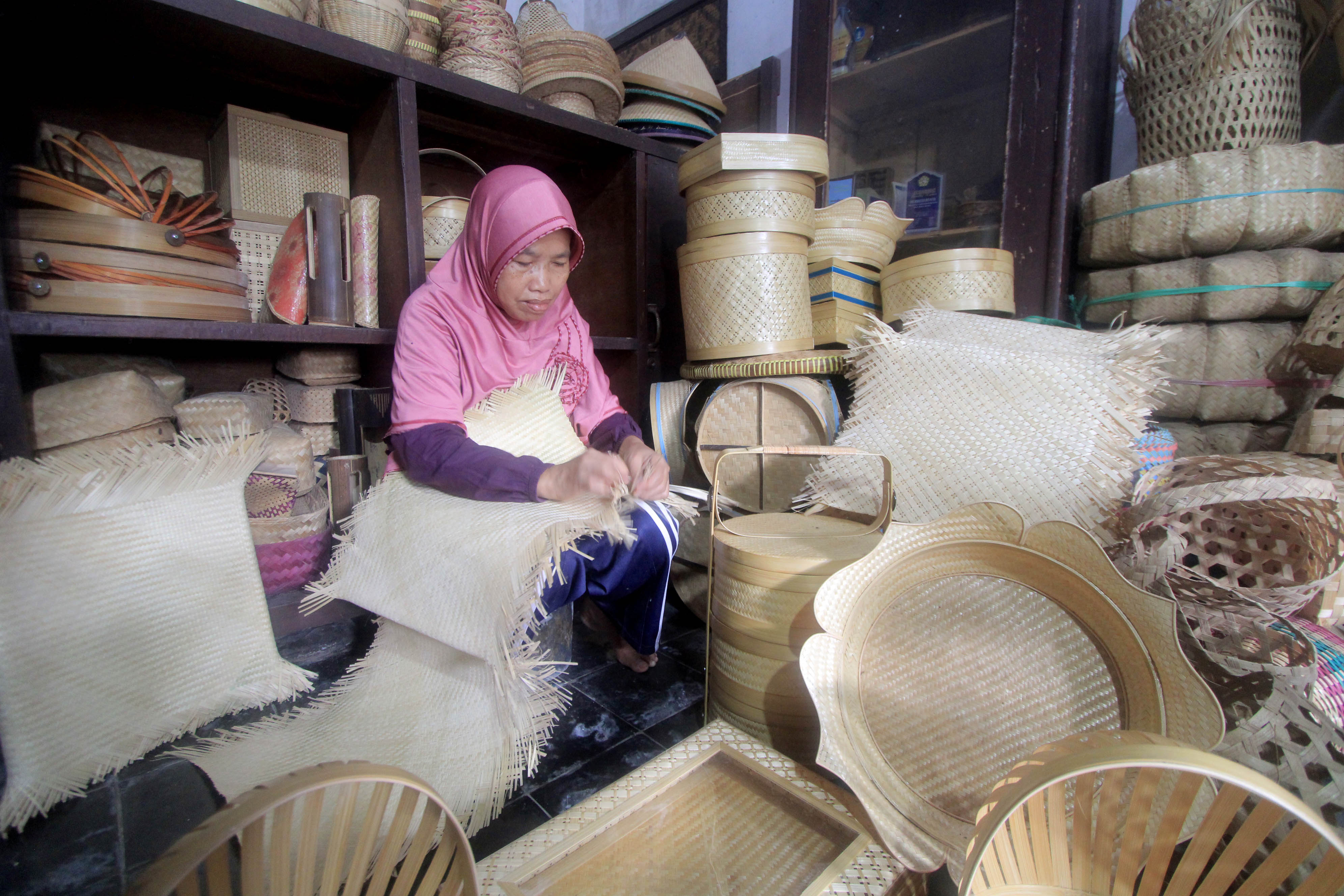 TELATEN: Sumiati menyelesaikan pesanan kerajinan bambu di rumahnya di Desa Ringinagung, Kecamatan Magetan.