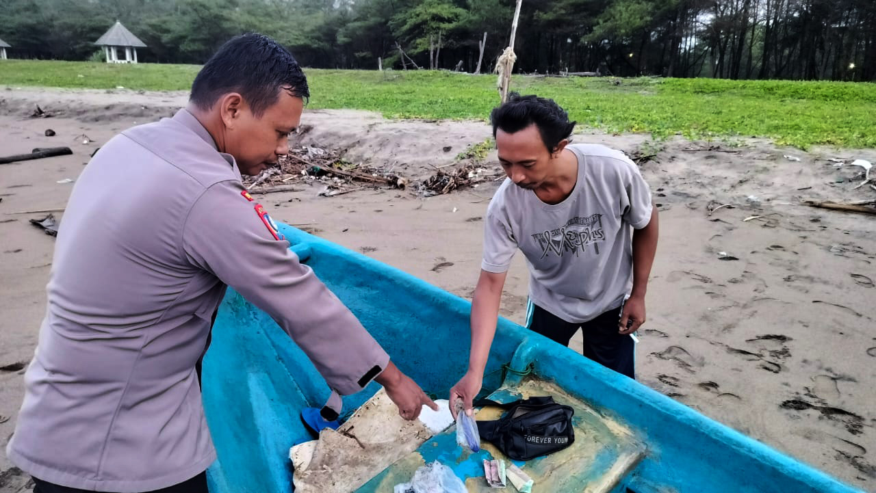 MENEPI: Petugas mengamankan perahu beserta perlengkapan korban laka air yang terdampar di Pantai Pancer Door, Pacitan, kemarin (15/1). (NUR CAHYONO/RADAR PACITAN)