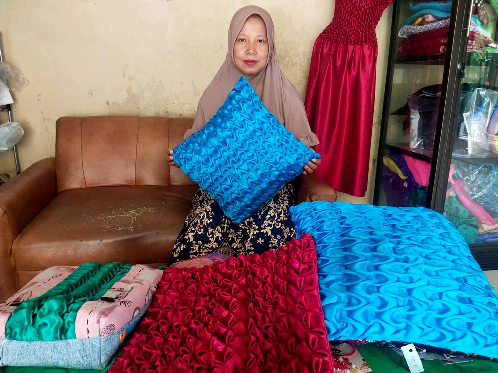 TEKUN: Sri Ismiyati menunjukkan beberapa produk sarung bantal yang dibuatnya.&nbsp;(ABRIYANTO/RADAR MADIUN)