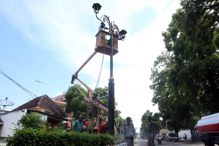 DIKUKUTI: Petugas Dishub Ponorogo membongkar PJU di sepanjang Jalan Ahlan dan Sultag sebelum median dibongkar.