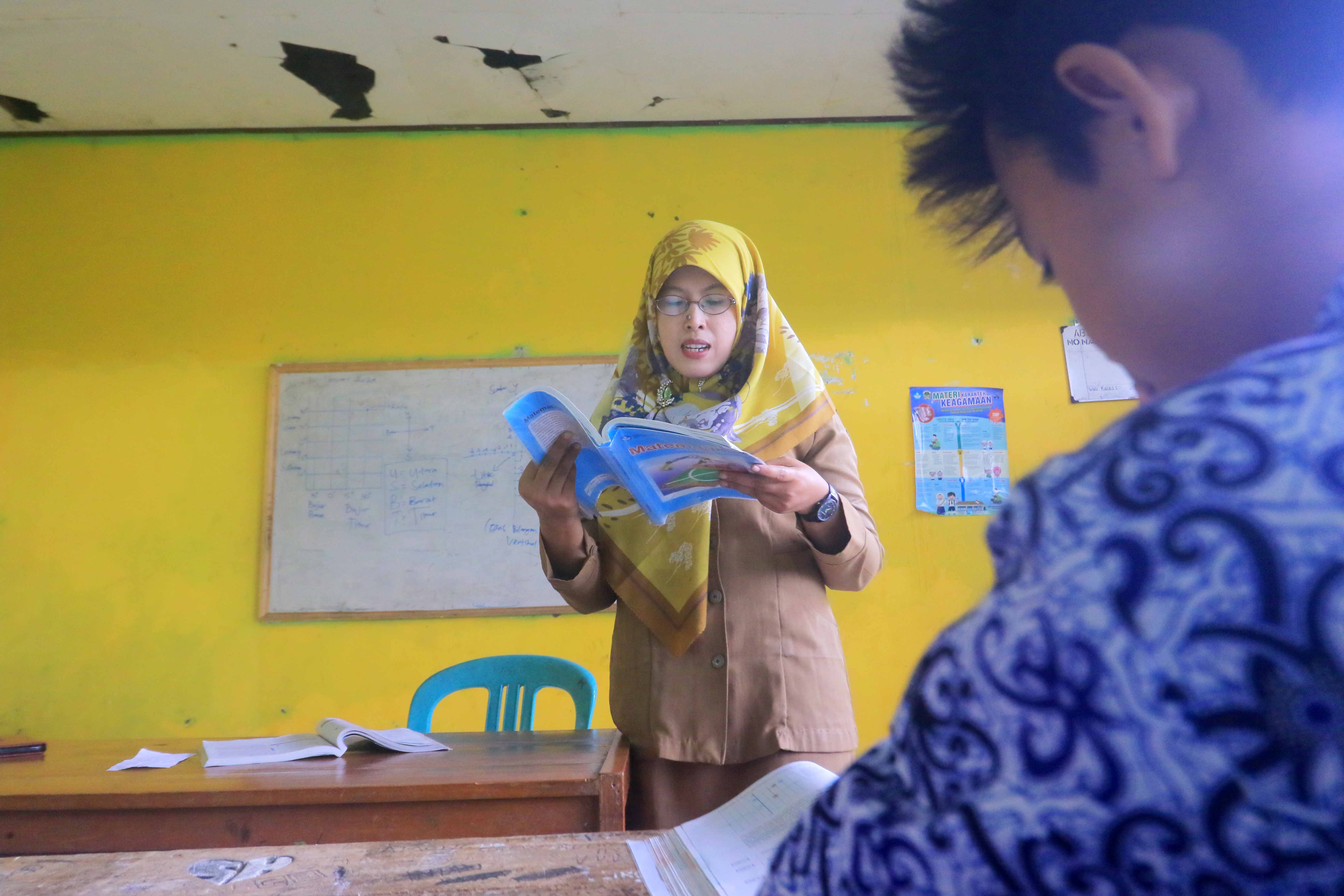 TULUS MENGADBI: Dian Widiyawati, guru SMPN Satu Atap Gemarang ketika beraktivitas di ruang kelas bersama anak didiknya.&nbsp;(R. BAGUS RAHADI/RADAR MADIUN)