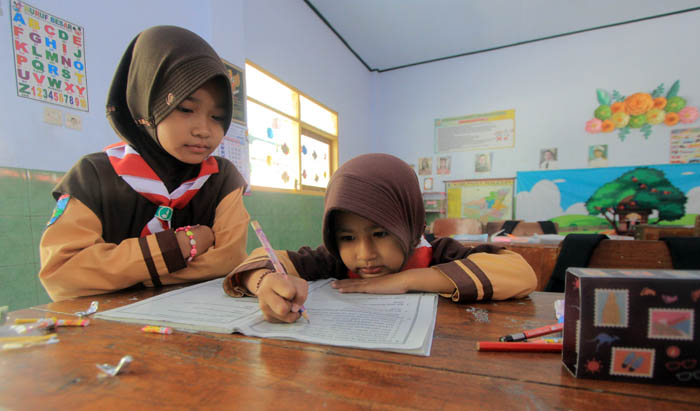 Ilustrasi dua siswi SD belajar di dalam kelas.