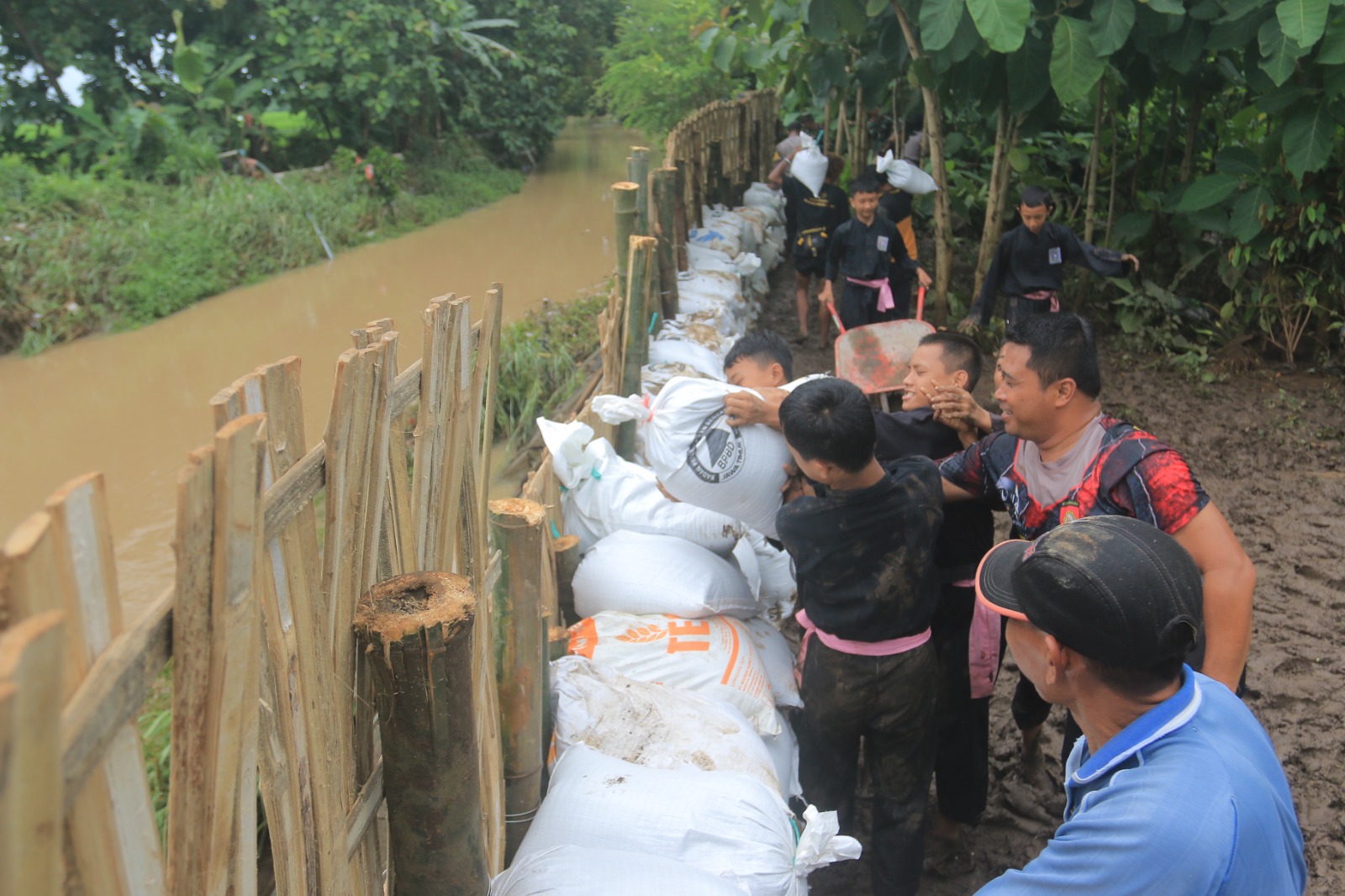 DAMPAK BANJIR: Petugas gabungan BPBD, TNI/Polri, dan kelurahan dibantu masyarakat membangun tanggul darurat dari karung pasir di Kali Piring kemarin (10/3). (BAGAS BIMANTARA/JAWA POS RADAR MADIUN)