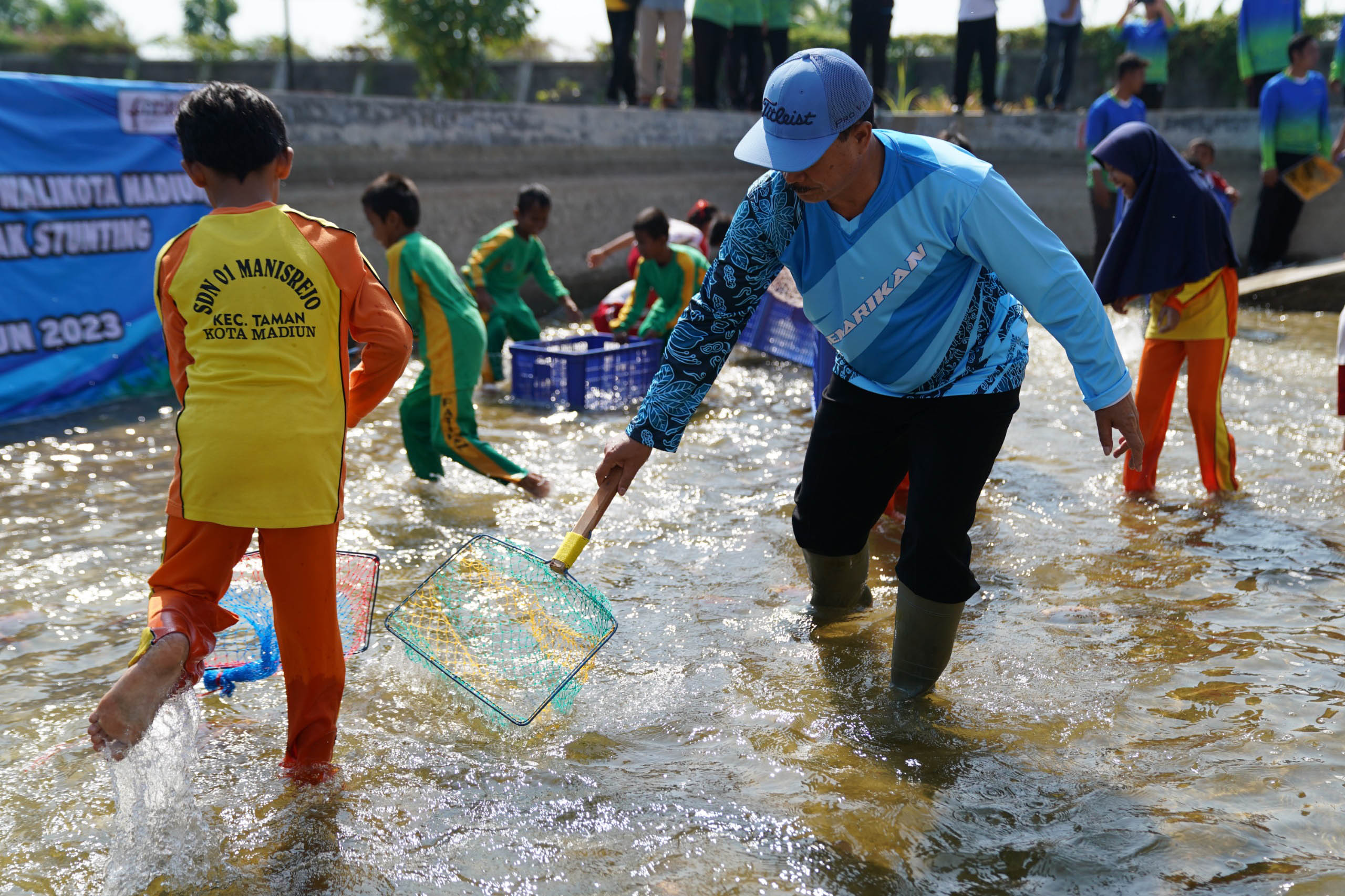 GEMARIKAN: Wali Kota Maidi menangkap ikan bersama dengan anak-anak SD di kolam yang berada di kompleks kantor DKPP Kota Madiun. (BAGAS BIMANTARA/JAWA POS RADAR MADIUN)