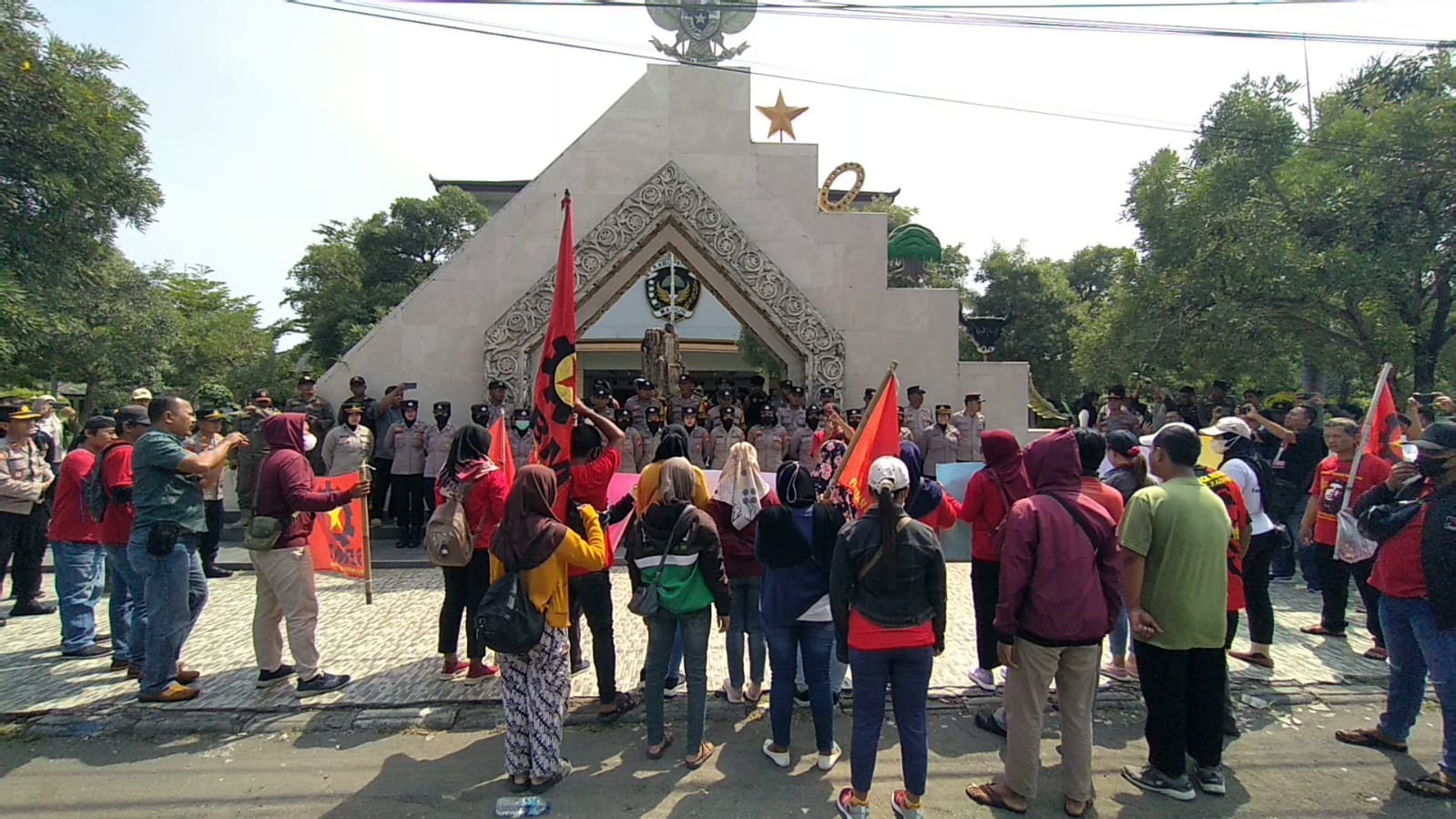 PRIHATIN: Massa SMBR melakukan aksi tabur bunga di depan kantor DPRD Kabupaten Madiun dengan pengawalan petugas kepolisian, Rabu (1/5). (R. BAGUS RAHADI/RADAR CARUBAN)