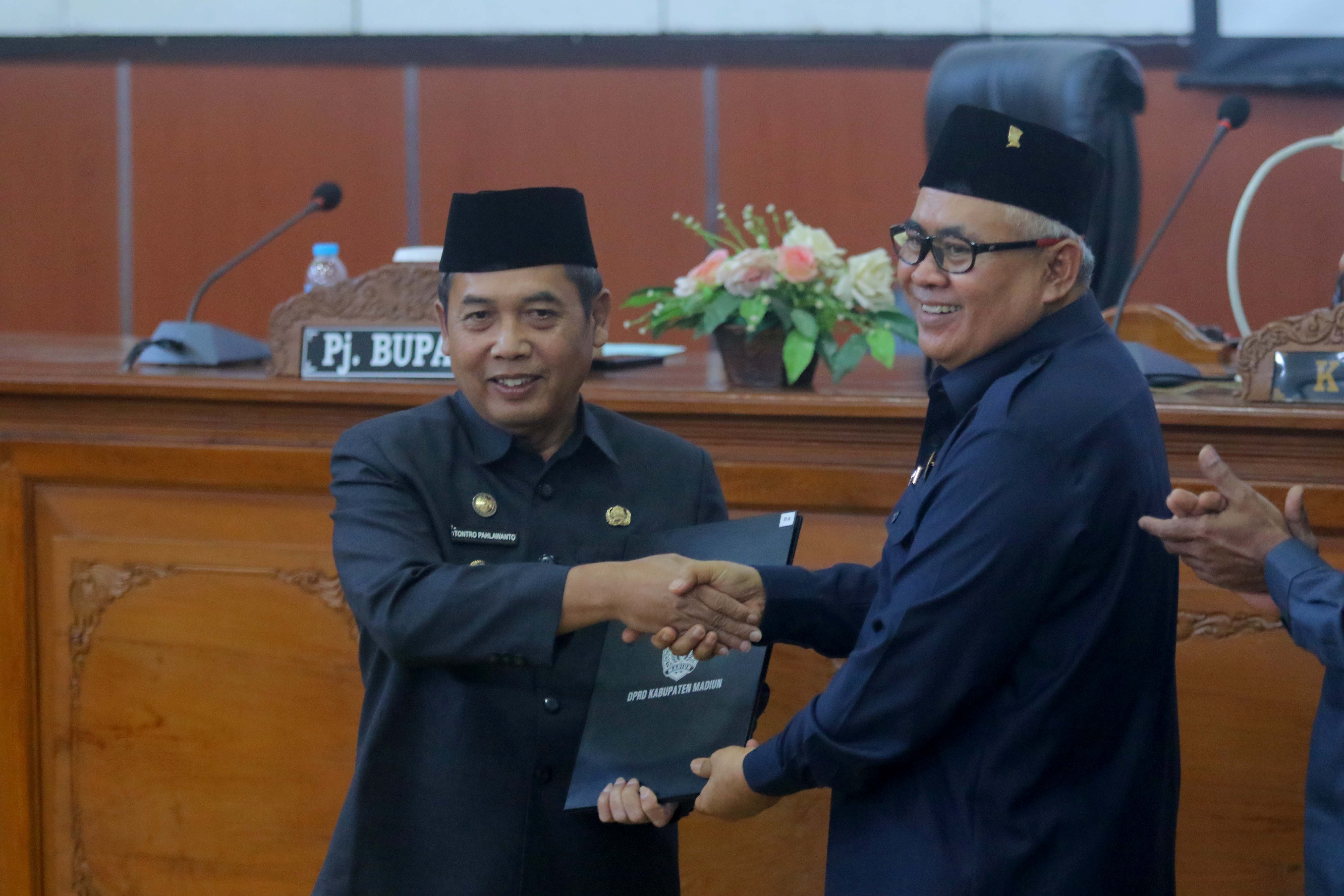 KOMPAK: Ketua DPRD Kabupaten Madiun Fery Sudarsono menyerahkan berita acara penetapan raperda pemberian insentif dan kemudahan investasi kepada Pj Bupati Madiun Tontro Pahlawanto, kemarin (16/5).