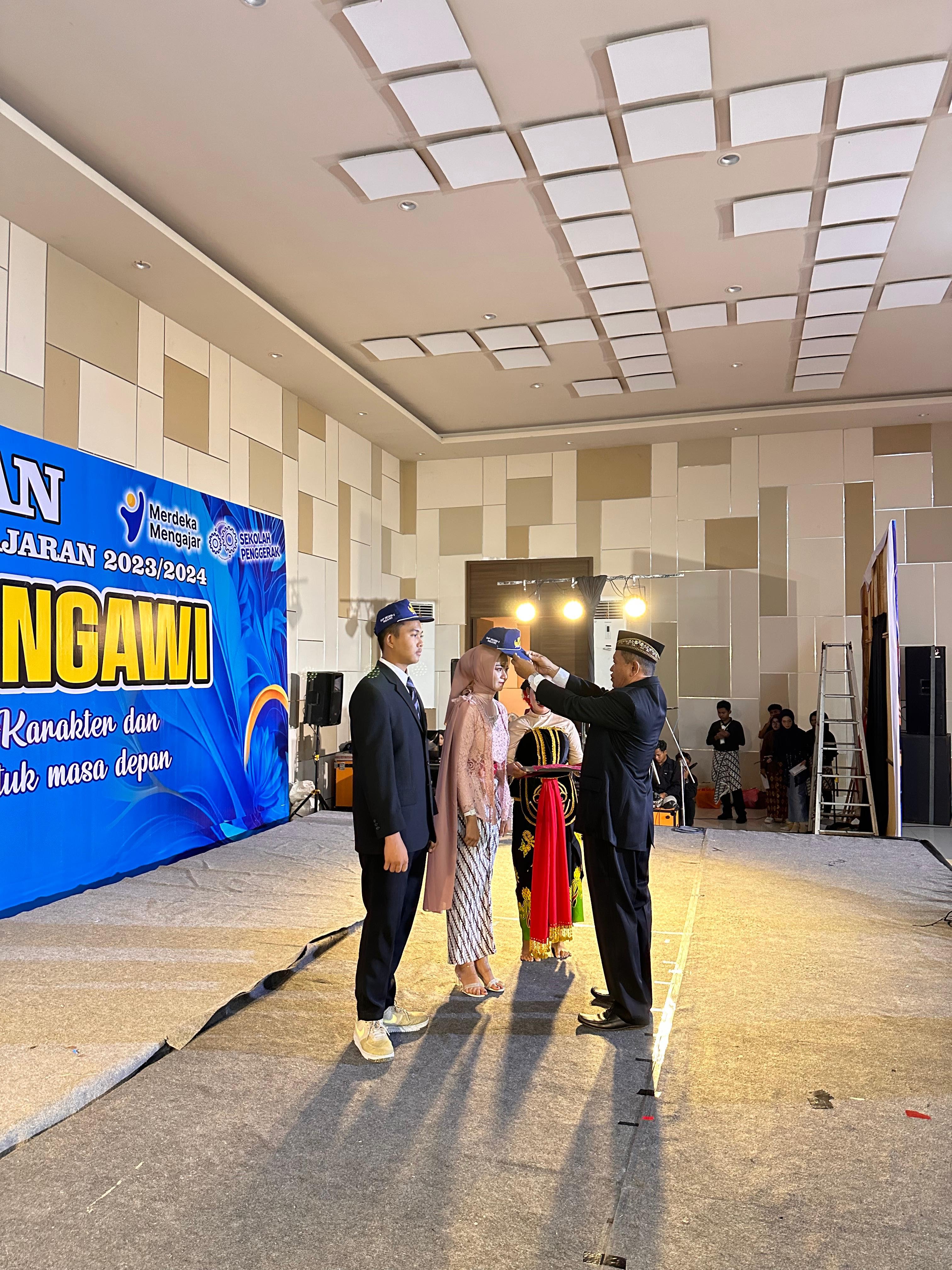 SIMBOLIS: Kepala SMPN 5 Ngawi Tarkum menanggalkan topi almamater yang dipakai purnawiyata siswa kelas IX kemarin. (LATIFATUL AFIFA/RADAR NGAWI)