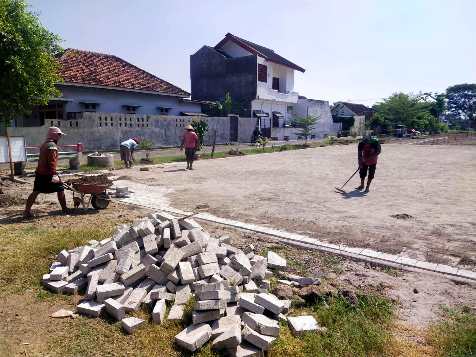 DIKEBUT: Para pekerja saat menyelesaikan pembangunan tempat parkir lapangan dengan menggunakan paving block. (ABRIANTO WIBOWO/RADAR MADIUN)