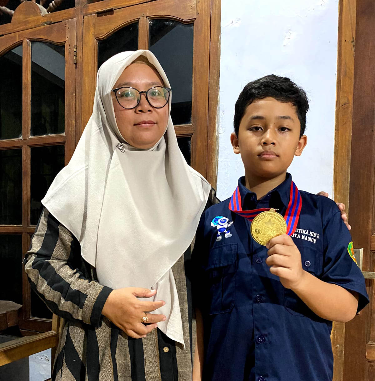 BANGGA: Dzakiy Adya Putra Herlino bersama ibundanya, Elien Putri menunjukkan medali emas kategori poin di International Robotics Talent Competition 2024 di Malaysia. (DIAN RAHAYU/RADAR MADIUN)