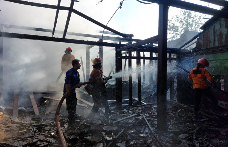 JINAKKAN SI JAGO MERAH: Petugas pemadam kebakaran membasahi salah satu rumah yang terbakar di Ngawi beberapa waktu lalu.