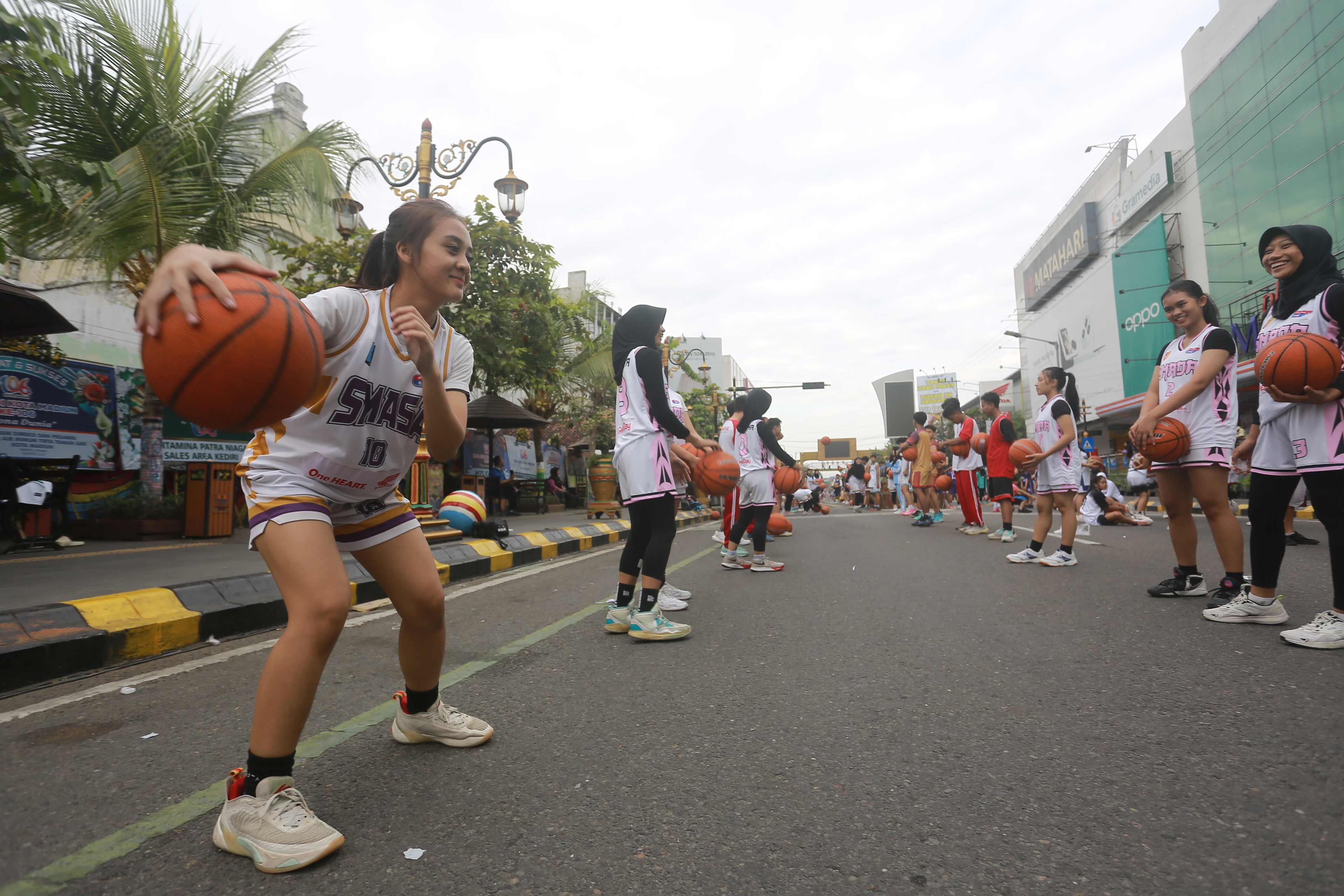 SPORTAINMENT: Para pelajar mengikuti pemecahan rekor MURI dribbling bola basket di Pahlawan Street Center, Minggu (23/6). (BAGAS BIMANTARA/RADAR MADIUN)