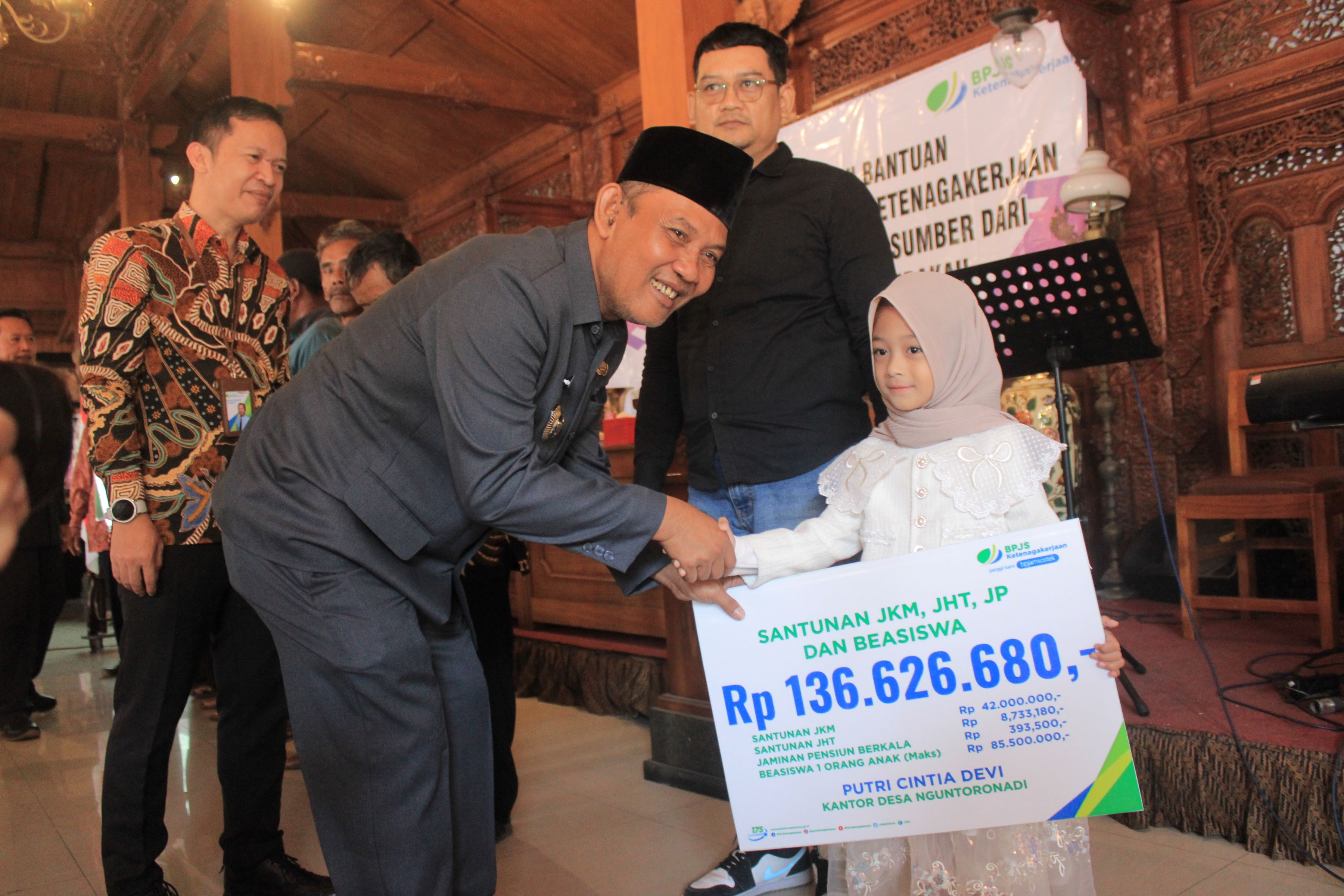 SALURKAN: Pj Bupati Magetan Hergunadi didampingi Kepala BPJS Ketenagakerjaan Cabang Madiun Anwar Hidayat (berbatik) saat menyerahkan santunan kepada ahli waris mendiang Sekdes Nguntoronadi.