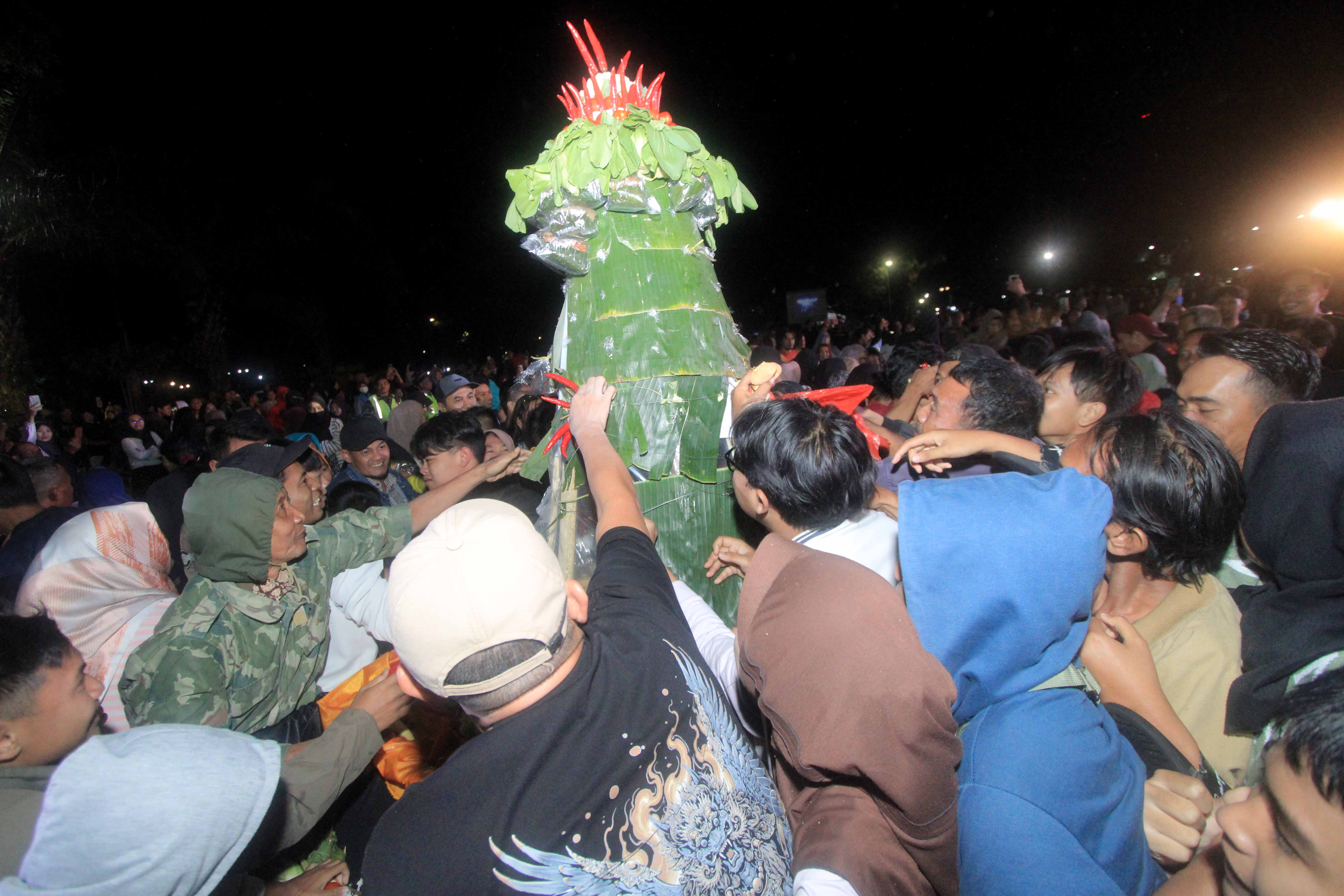 KEARIFAN LOKAL: Warga berebut gunungan saat Kirab Gumolong Lampah Hastungkara Andum Bolu Rahayu, Kamis (11/7) lalu.&nbsp;(AJI PUTRA/RADAR MAGETAN)