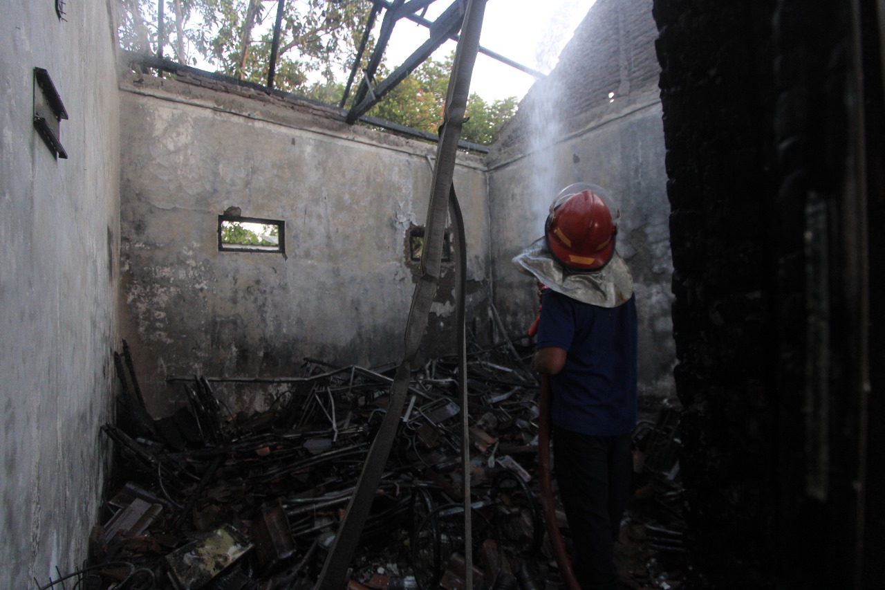 HANGUS: Petugas damkar memadamkan kebakaran di gudang milik Dinsos Magetan, Jumat (30/8).&nbsp;(AJI PUTRA/RADAR MAGETAN)