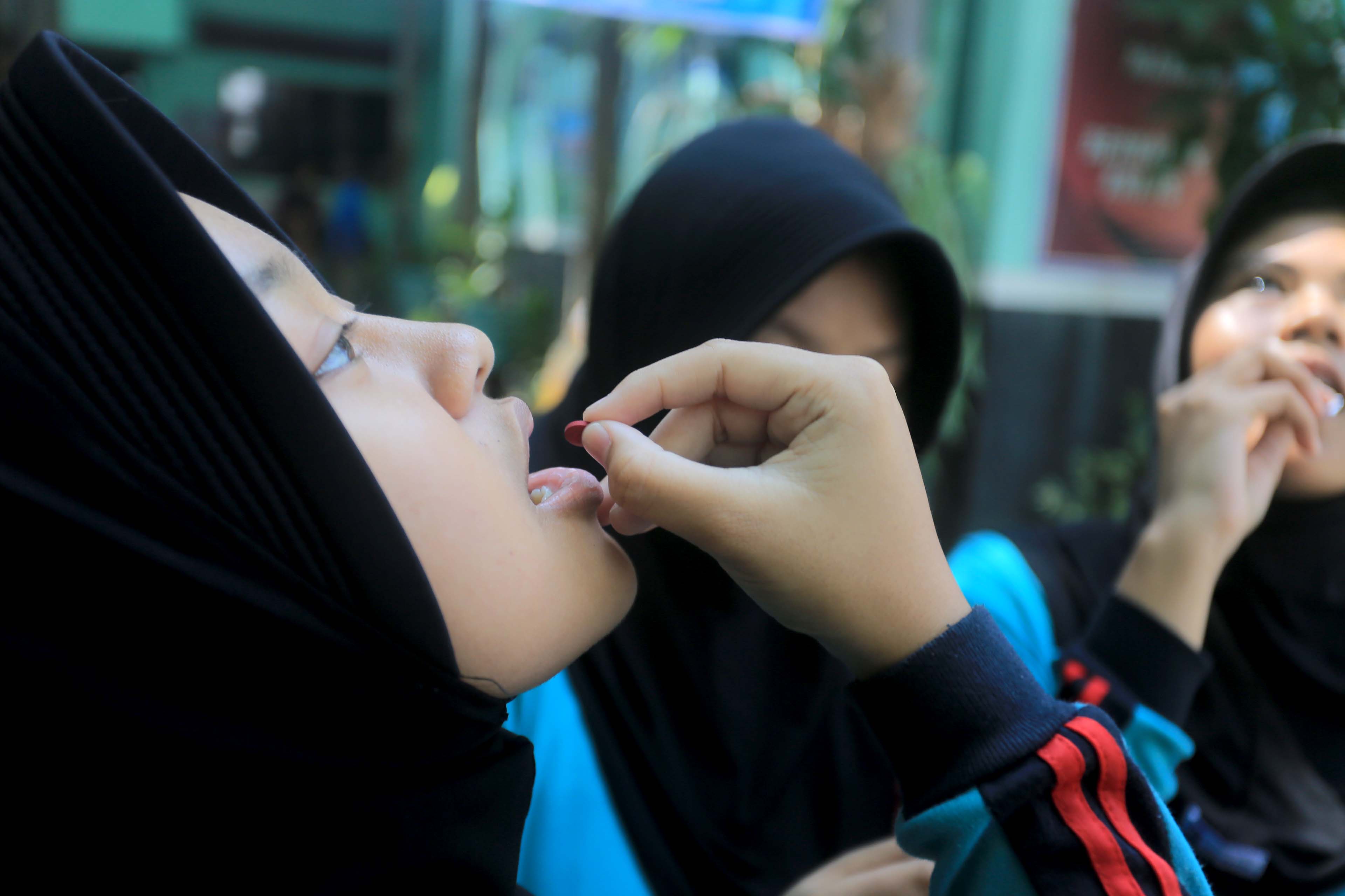 CEGAH STUNTING: Siswi SMPN 2 Kota Madiun mengonsumsi tablet tambah darah yang diberikan oleh dinkes-PPKB, Senin (9/9). (BAGAS BIMANTARA/RADAR MADIUN)&nbsp;