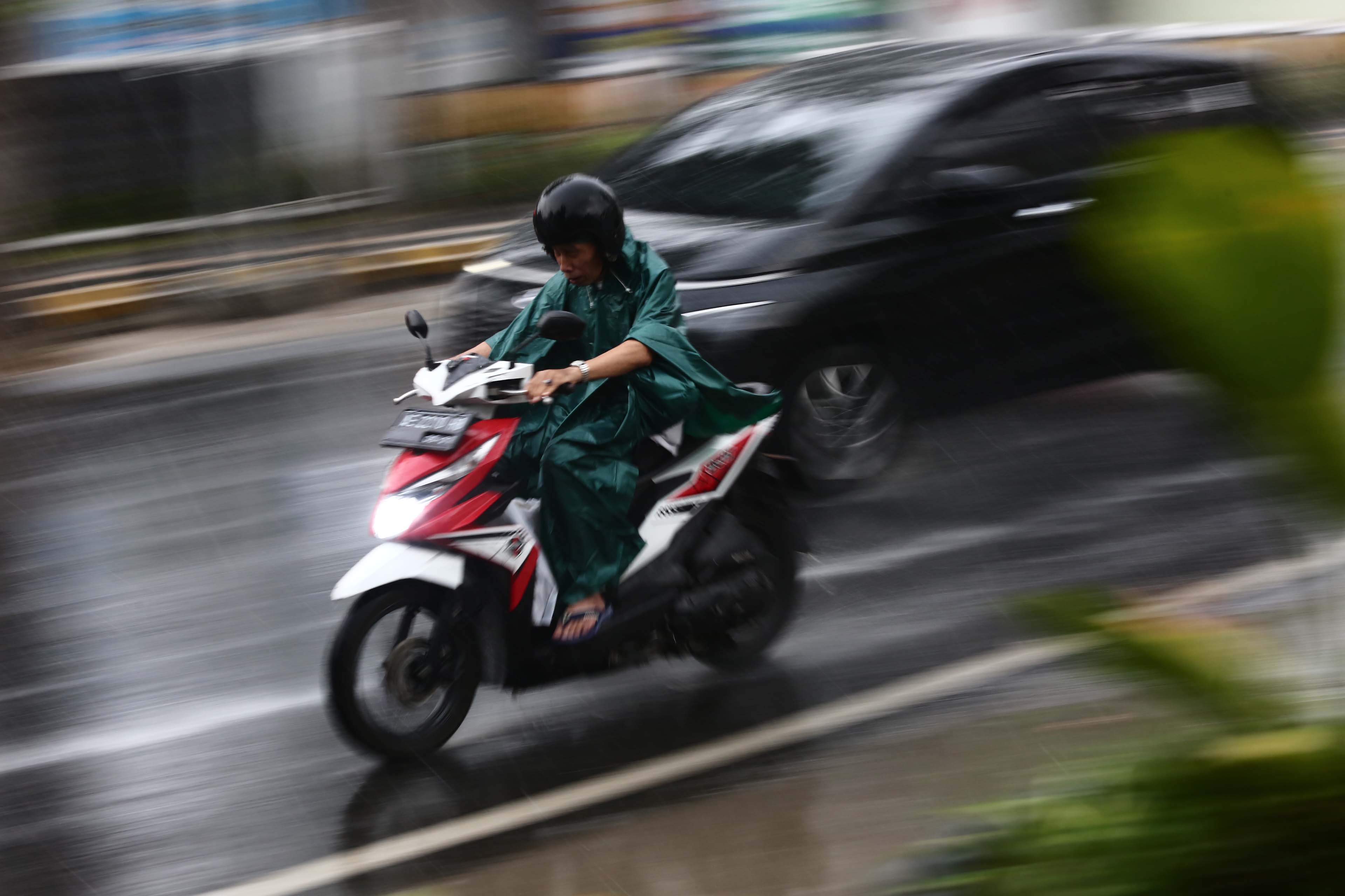 BASAH: Pengendara motor mengenakan jas hujan saat melintas di jalanan Kota Madiun.&nbsp;(BAGAS BIMANTARA/RADAR MADIUN)