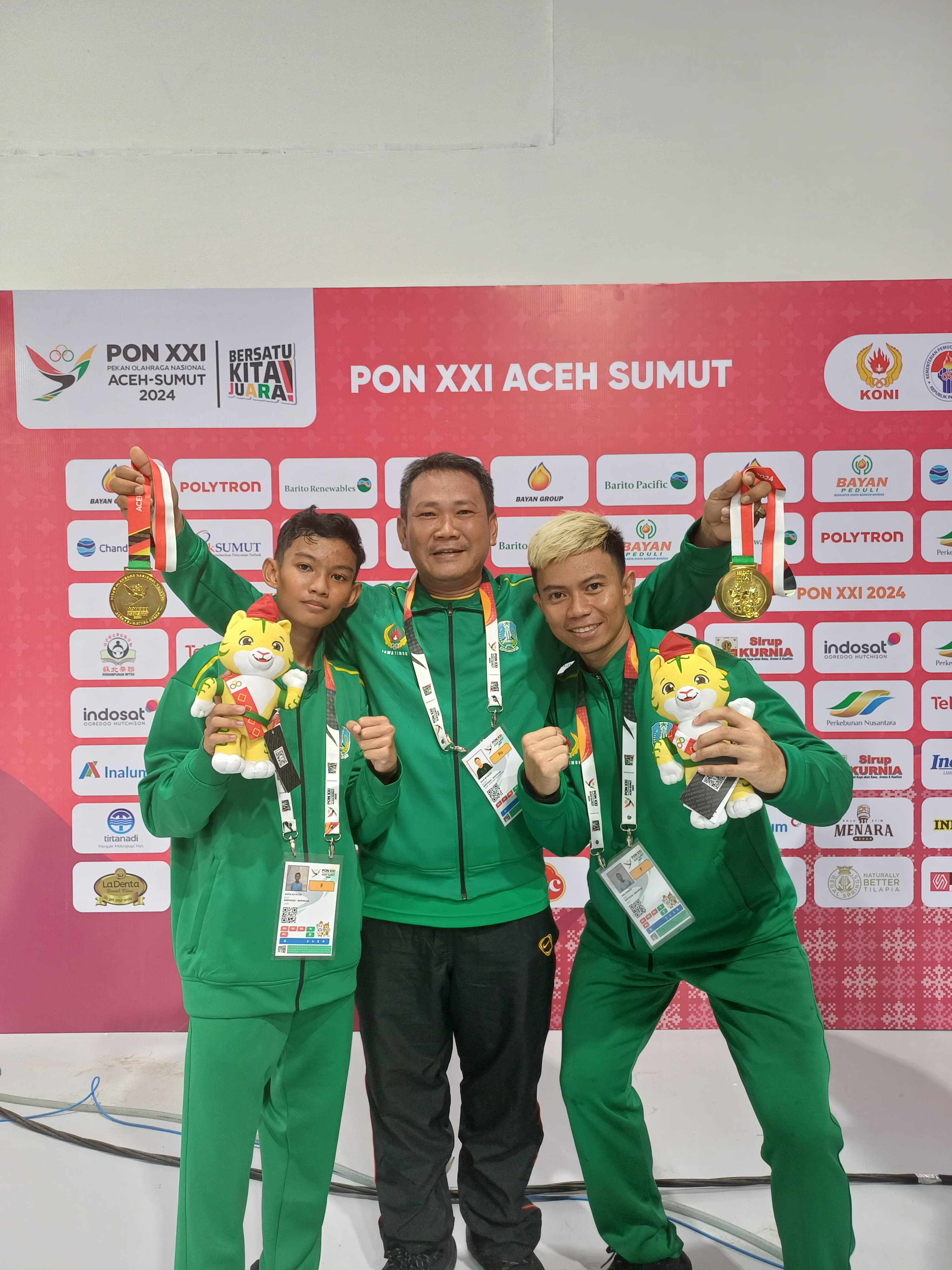 MONCER: Surya Adi Putra dan Heru Iswanto saat menerima medali emas cabor barongsai di PON 2024. (ABRIANTO WIBOWO/RADAR MADIUN)