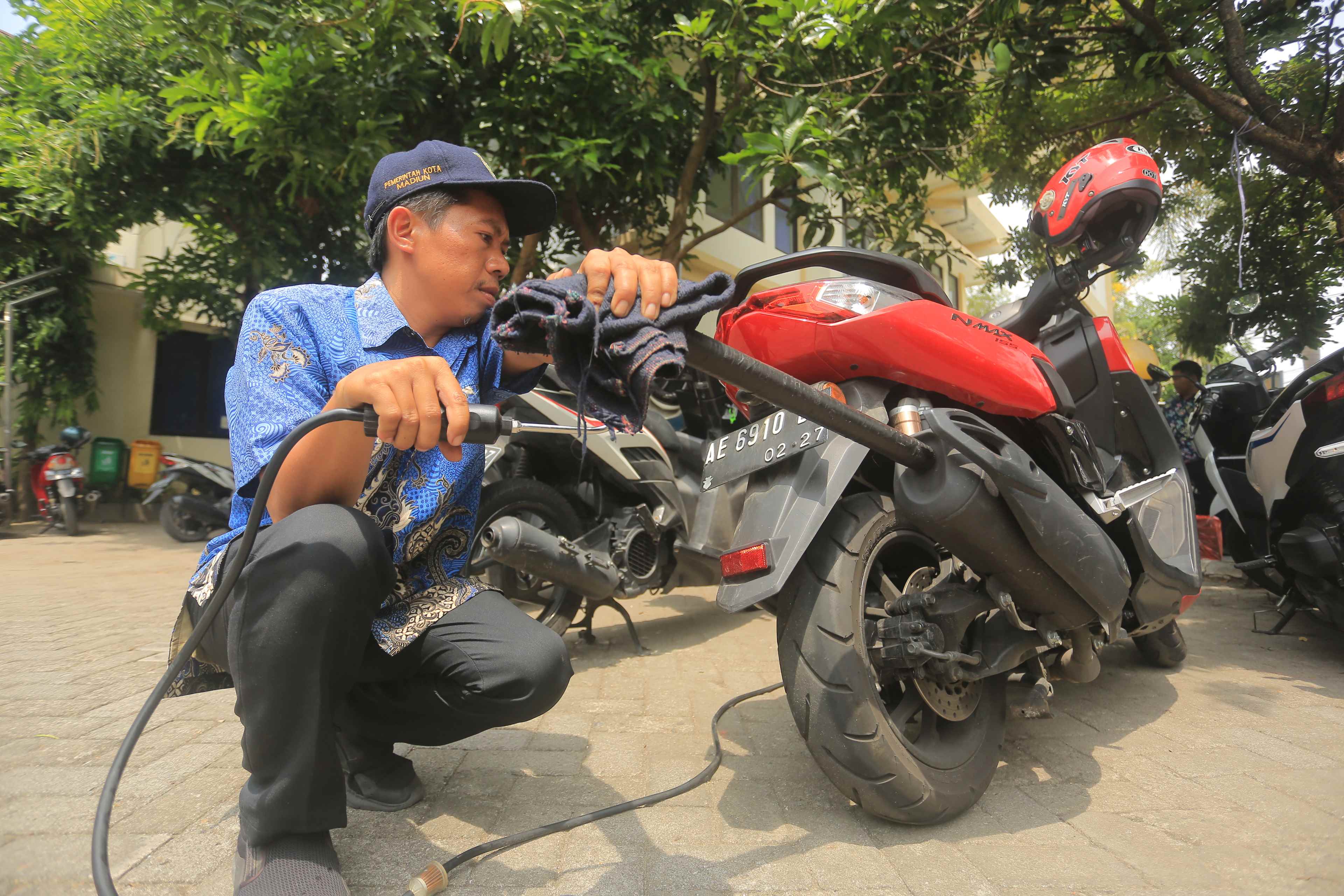 CEK EMISI: Petugas dari DLH Kota Madiun melakukan uji emisi terhadap kendaraan warga di halaman kantor Kelurahan Patihan, Kamis (3/10). (BAGAS BIMANTARA/RADAR MADIUN)