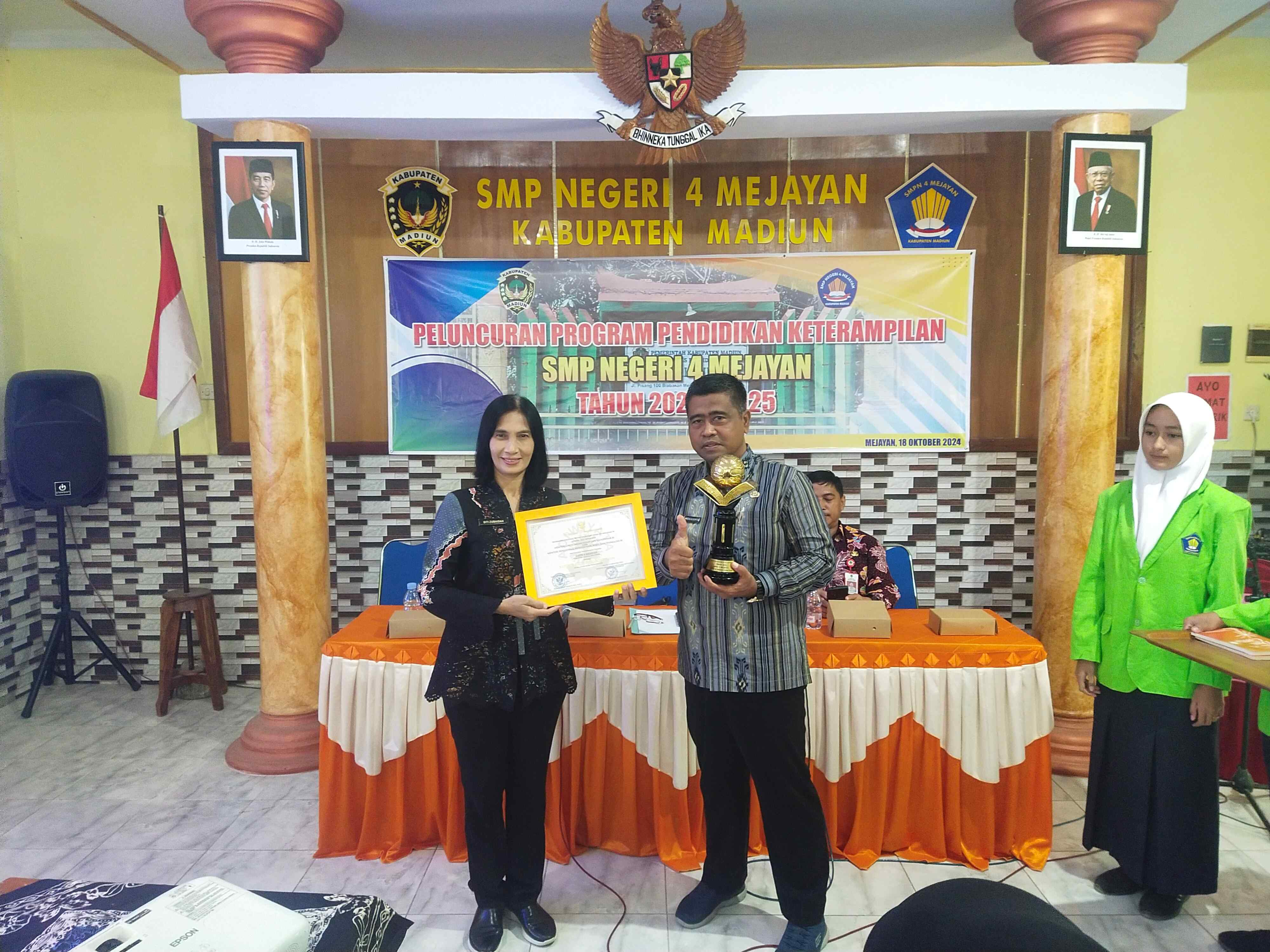 MONCER: Kepala Dikbud Kabupaten Madiun Siti Zubaidah dan Plt Kepala SMPN 4 Mejayan Agus Sucipto menunjukkan piala dan piagam Sekolah Adiwiyata Mandiri 2024.&nbsp;(TITIS OSI/RADAR MADIUN)