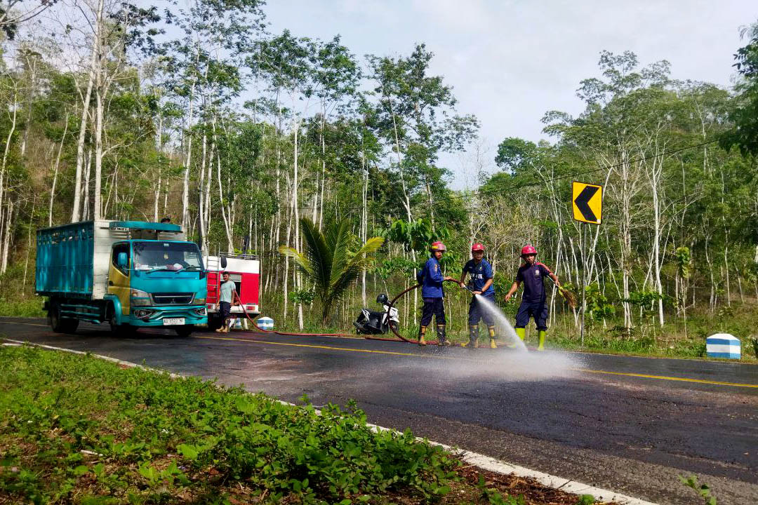 JALUR NASIONAL: Petugas Damkar Punung membersihkan tumpahan solar di Jalan Gunung Rondo, ruas Dusun Kladen, Desa Sooka, Kecamatan Punung.&nbsp;(NUR CAHYONO/RADAR MADIUN)