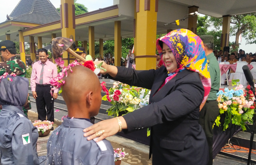 RESMI: Kepala SMKN 1 Wonoasri Wiwik Wiyati menyiram kembang dan memasangkan tanda dilantiknya taruna-taruni.&nbsp;(ABRIANTO WIBOWO/RADAR MADIUN)