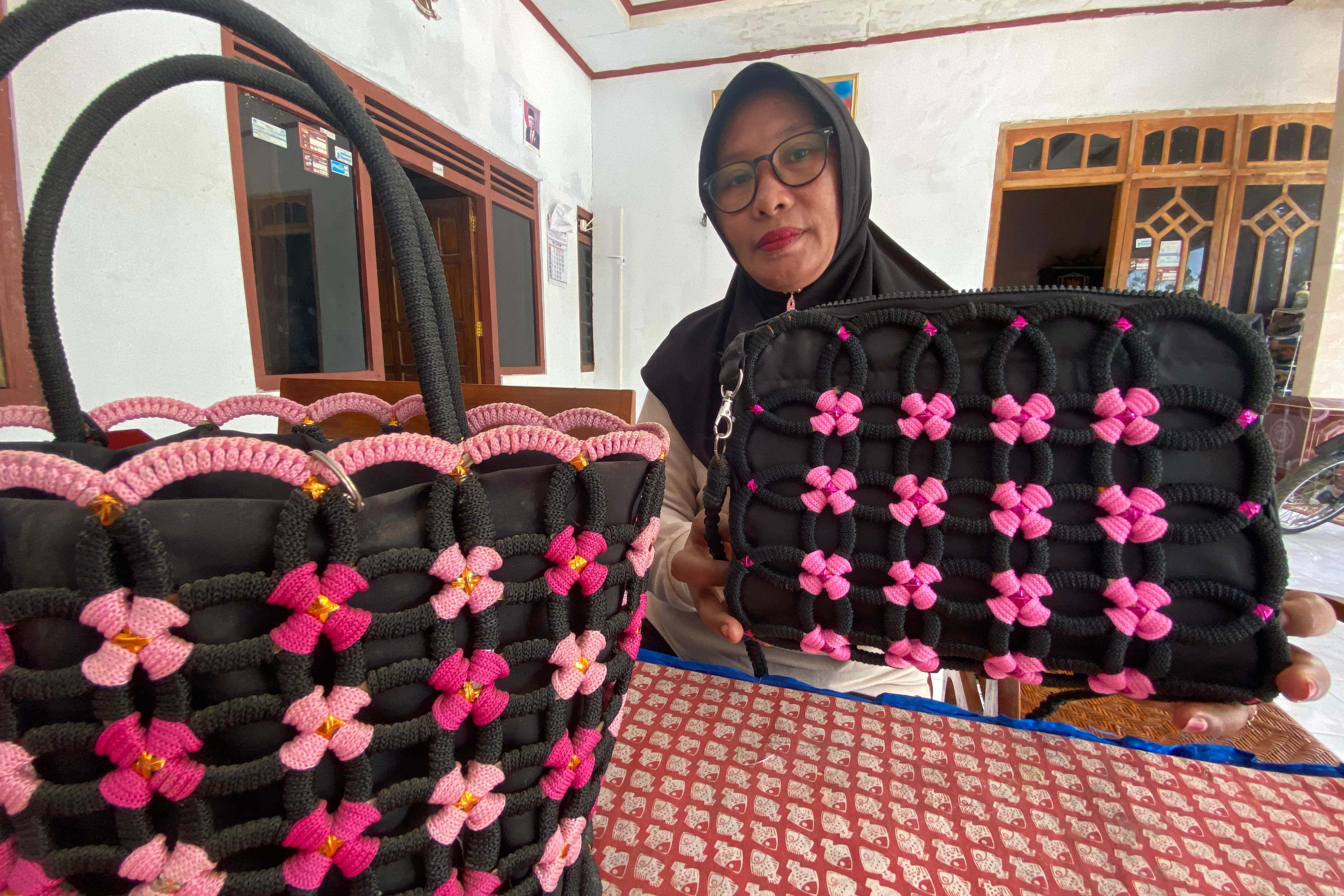 INOVATIF: Winarti menunjukkan tas hasil daur ulang gelas plastik bekas buatannya. (DIAN RAHAYU/RADAR MADIUN)