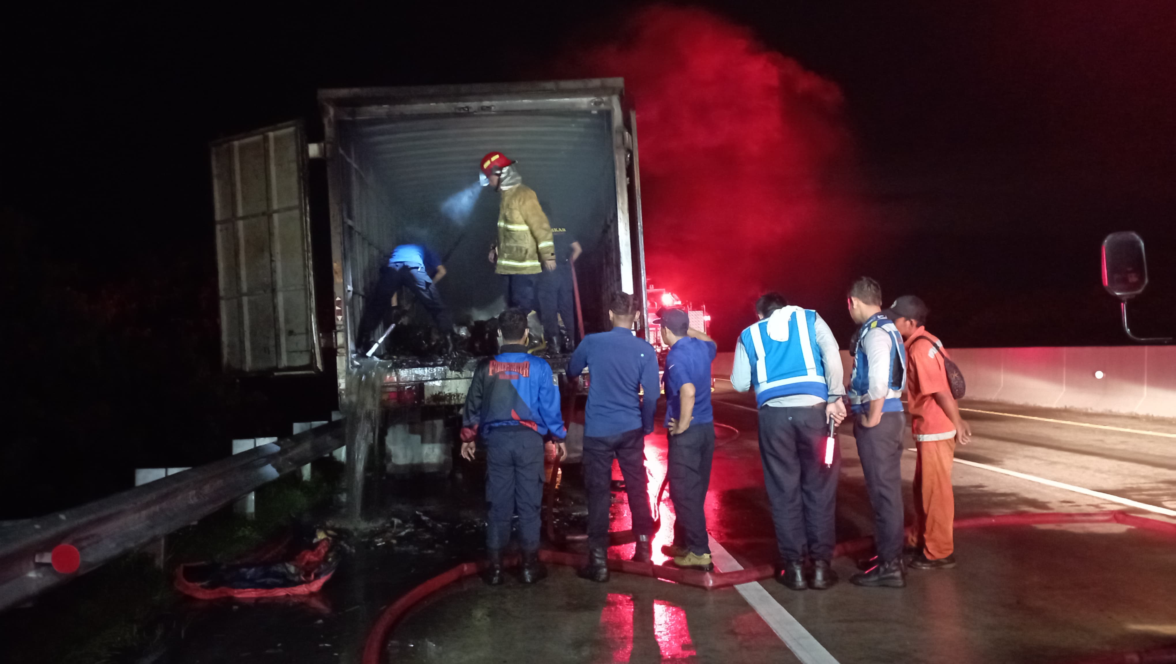 PENDINGINAN: Petugas Damkar dari Ngawi memadamkan api yang berkobar dalam truk ekspedisi milik PT Pos Logistik Indonesia di Tol Ngawi-Madiun, Rabu (27/11). (AJI PUTRA/JAWA POS RADAR MAGETAN)