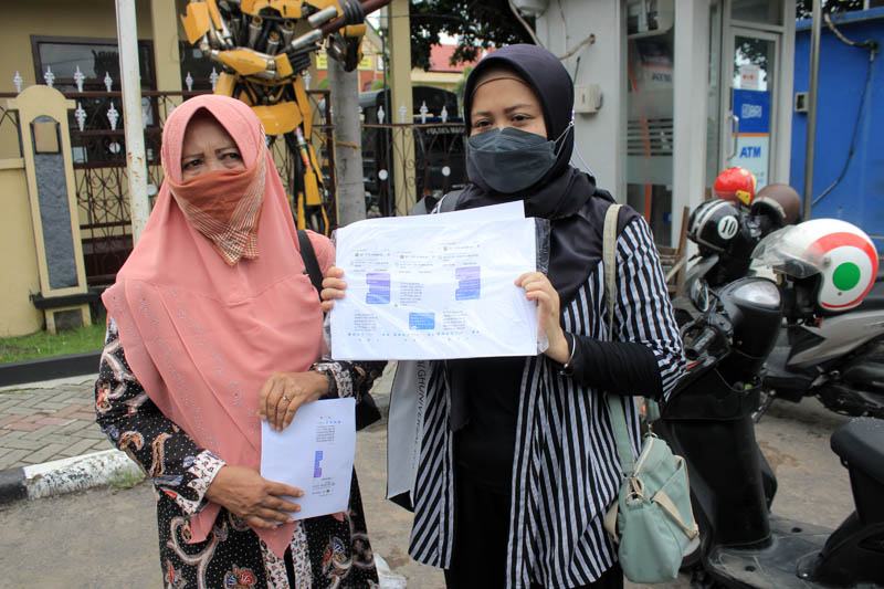 KEJAHATAN PHISING: Sri Fauzi dan anaknya menunjukkan bukti isi pesan dari pelaku penipuan di Mapolres Magetan, Senin (9/12).