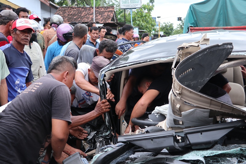 DRAMATIS: Warga mengevakuasi pengemudi mobil Xpander yang terjepit di ruang kemudi usai adu moncong dengan truk ekspedisi di Balong, Ponorogo, Rabu (25/12).
