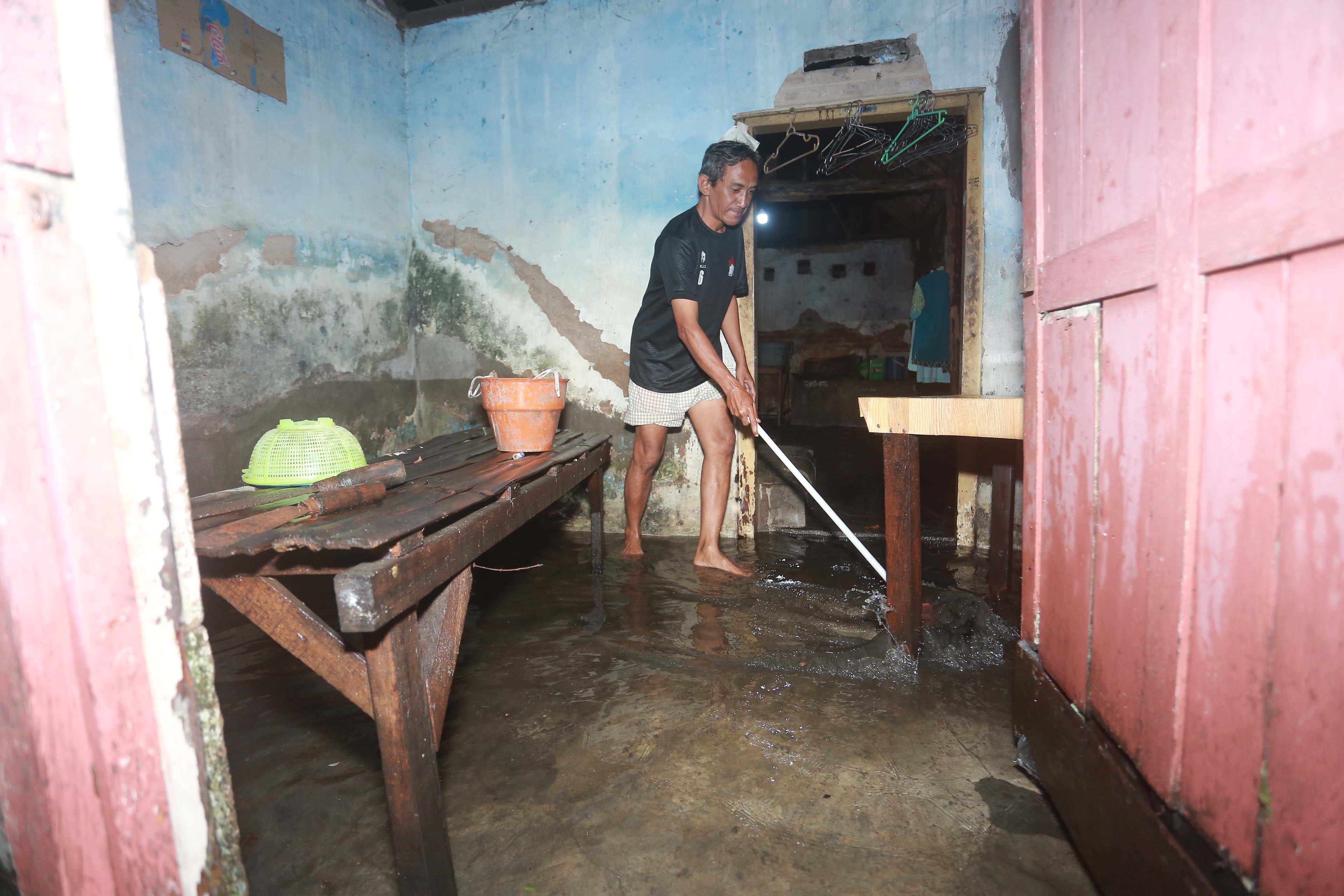 TERDAMPAK BANJIR: Seorang warga di Jalan Sultan Trenggono, Manguharjo, membersihkan rumah setelah banjir surut kemarin.
