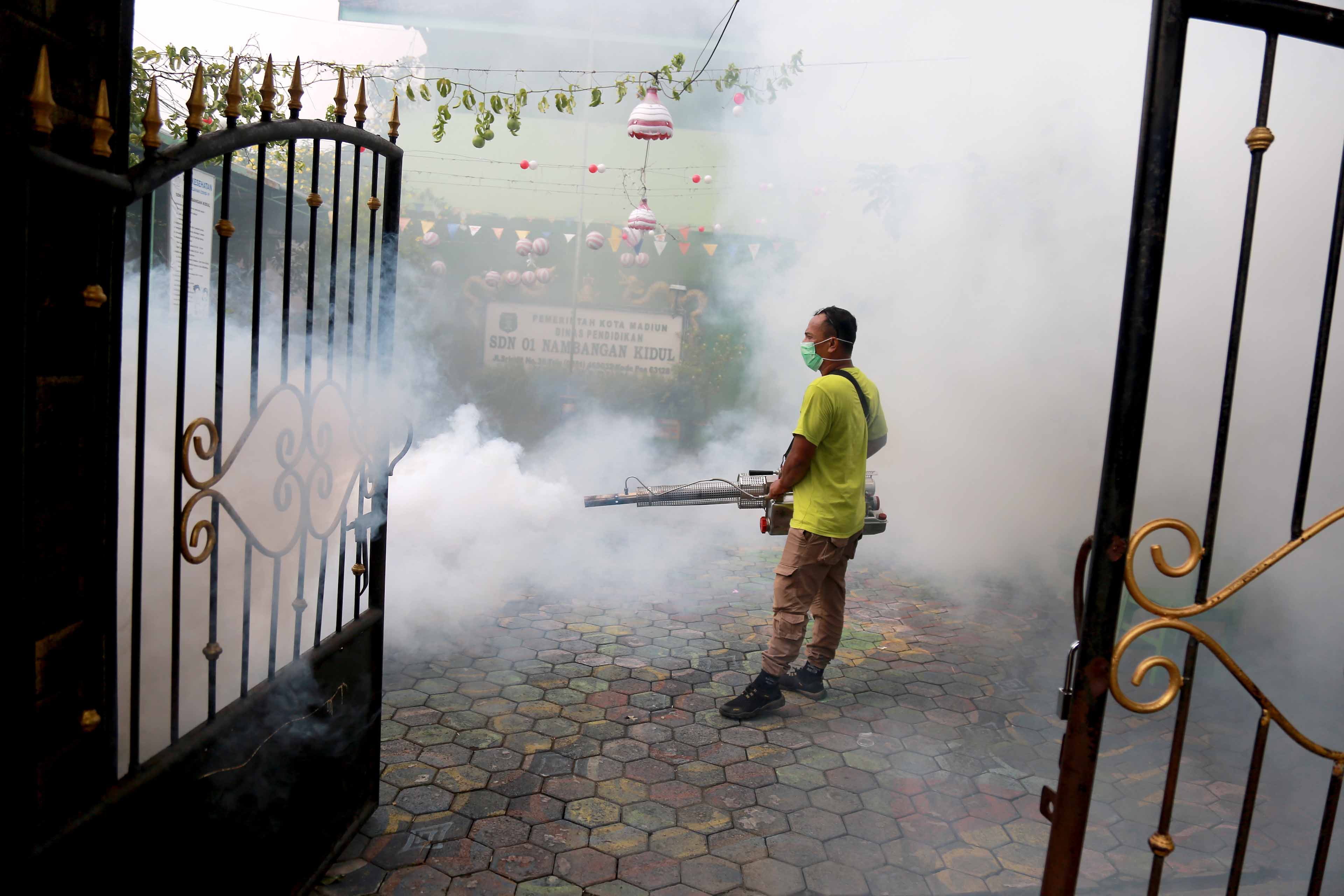 ENDEMIK: Petugas dari Dinkes-PPKB Kota Madiun melakukan pengasapan alias fogging di lingkungan SDN 03 Nambangan Kidul kemarin (16/1).