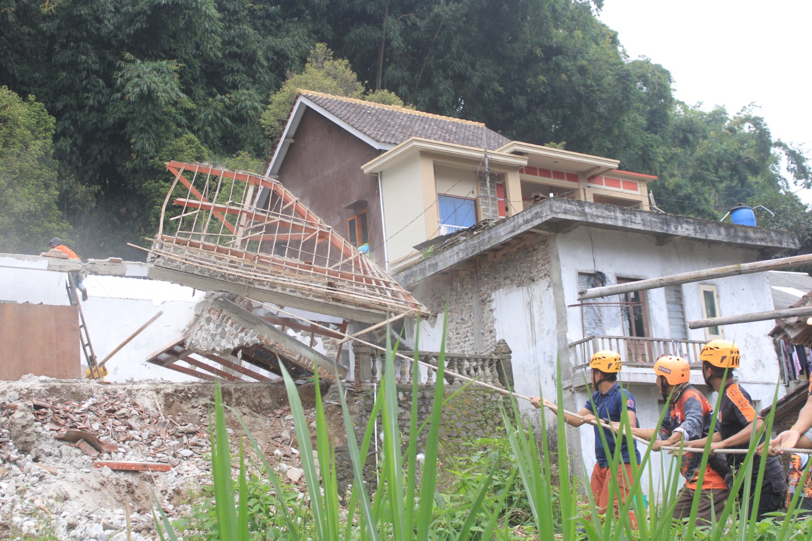 Petugas BPBD Magetan membantu proses evakuasi rumah korban longsor di Plaosan, Sabtu (8/2). (AJI PUTRA/RADAR MAGETAN)