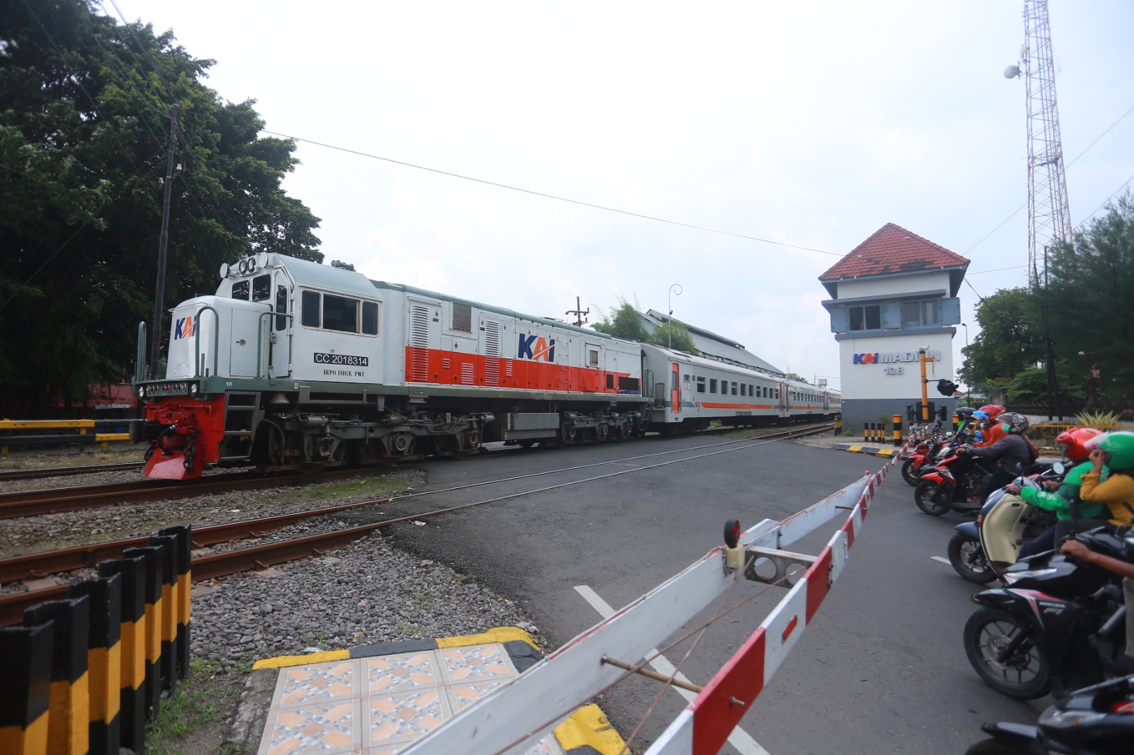 PERLINTASAN SEBIDANG: Sejumlah pengendara menunggu KA melintas di Kota Madiun. Daop 7 Madiun sediakan puluhan ribu tiket angkutan Lebaran tahun ini.