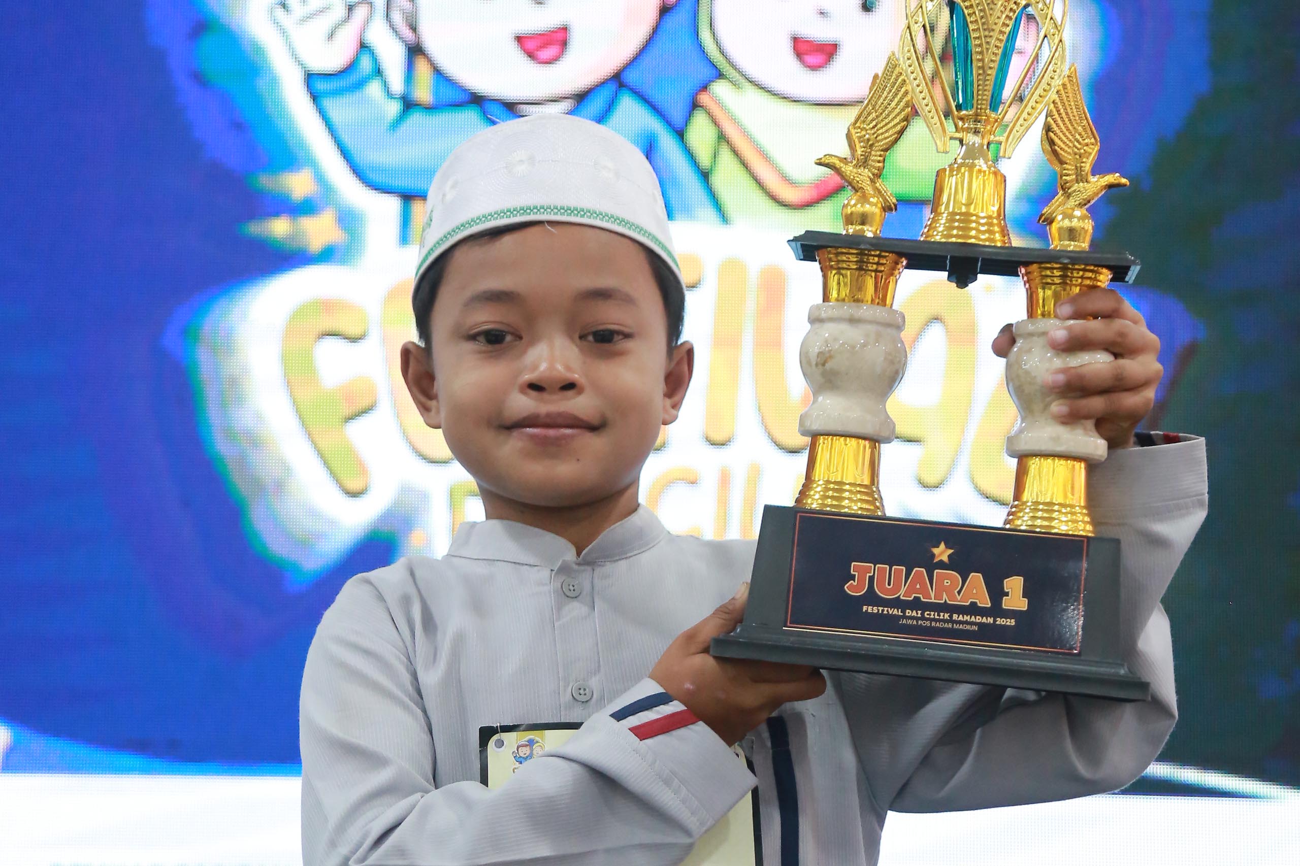 INSPIRATIF: Viky Arianto mengangkat trofi juara I Festival Dai Cilik 2025 Jawa Pos Radar Madiun.