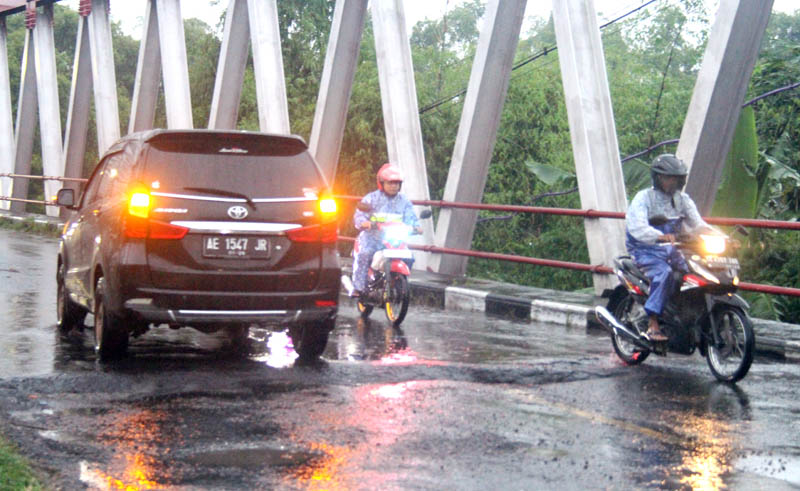RUSAK PARAH: Pengendara bermotor mengurangi kecepat untuk menghindari lubang di Jembatan Jetak, Ngawi.