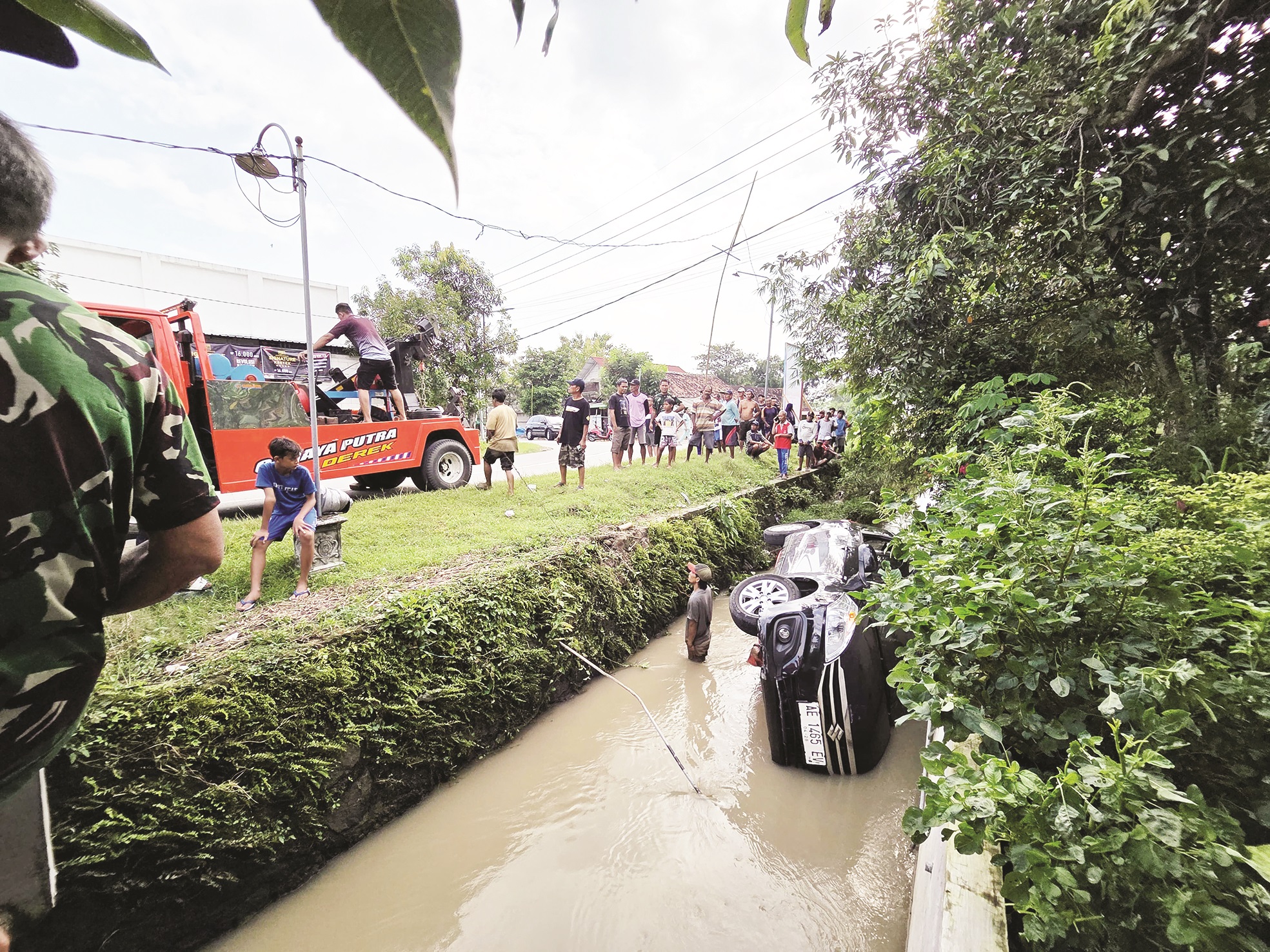 TERPEROSOK: Proses Evakuasi mobil Ertiga yang masuk parit di Desa Pilangkenceng, Kabupaten Madiun, Senin 3 Maret 2025.