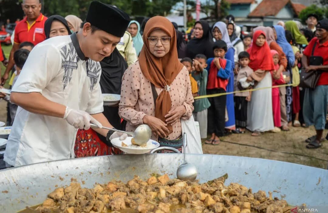 Kreator konten YouTube Bobon Santoso menuangkan ayam ke piring milik warga saat melakukan demo masak di Pinang, Kota Tangerang, Banten.