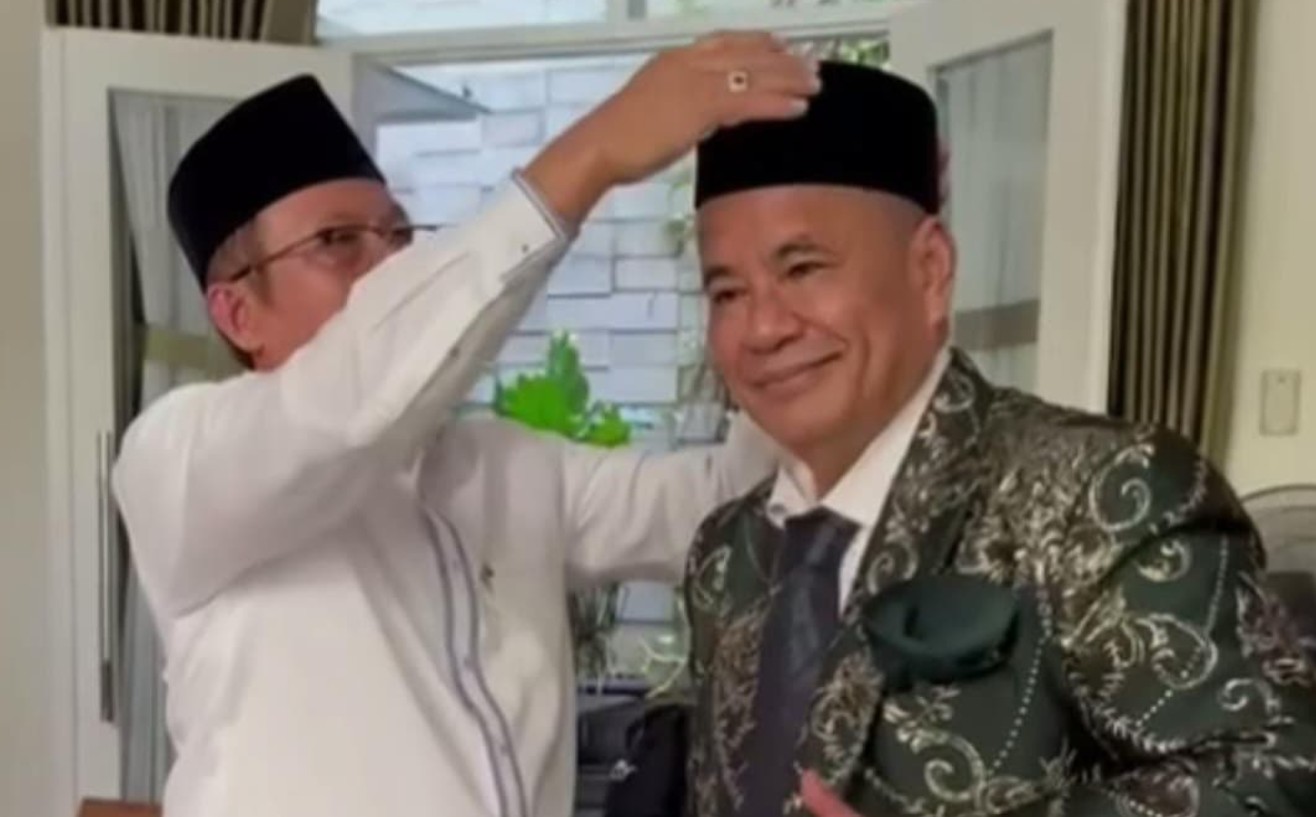 Momen Hotman Paris saat dipakaikan peci oleh Wakil Sekjen MUI Ihksan Abdullah.