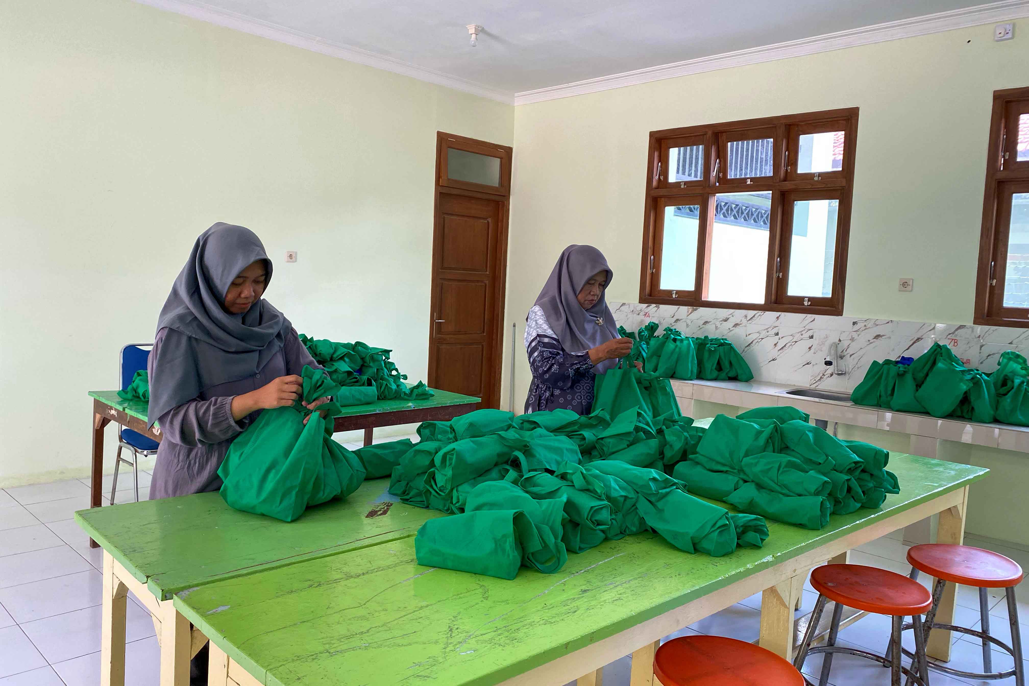 Guru SMPN 5 Madiun membagikan paket menu MBG yang telah didistribusikan oleh SPPG untuk ratusan siswa di sekolah tersebut, Rabu 12 Maret 2025.