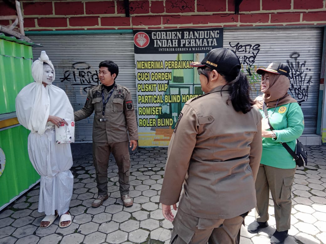 Satpol PP Kota Madiun mengamankan salah seorang pengamen dengan model pocong di simpang empat PGA kemarin. FOTO: SATPOL PP DAN DAMKAR KOTA MADIUN