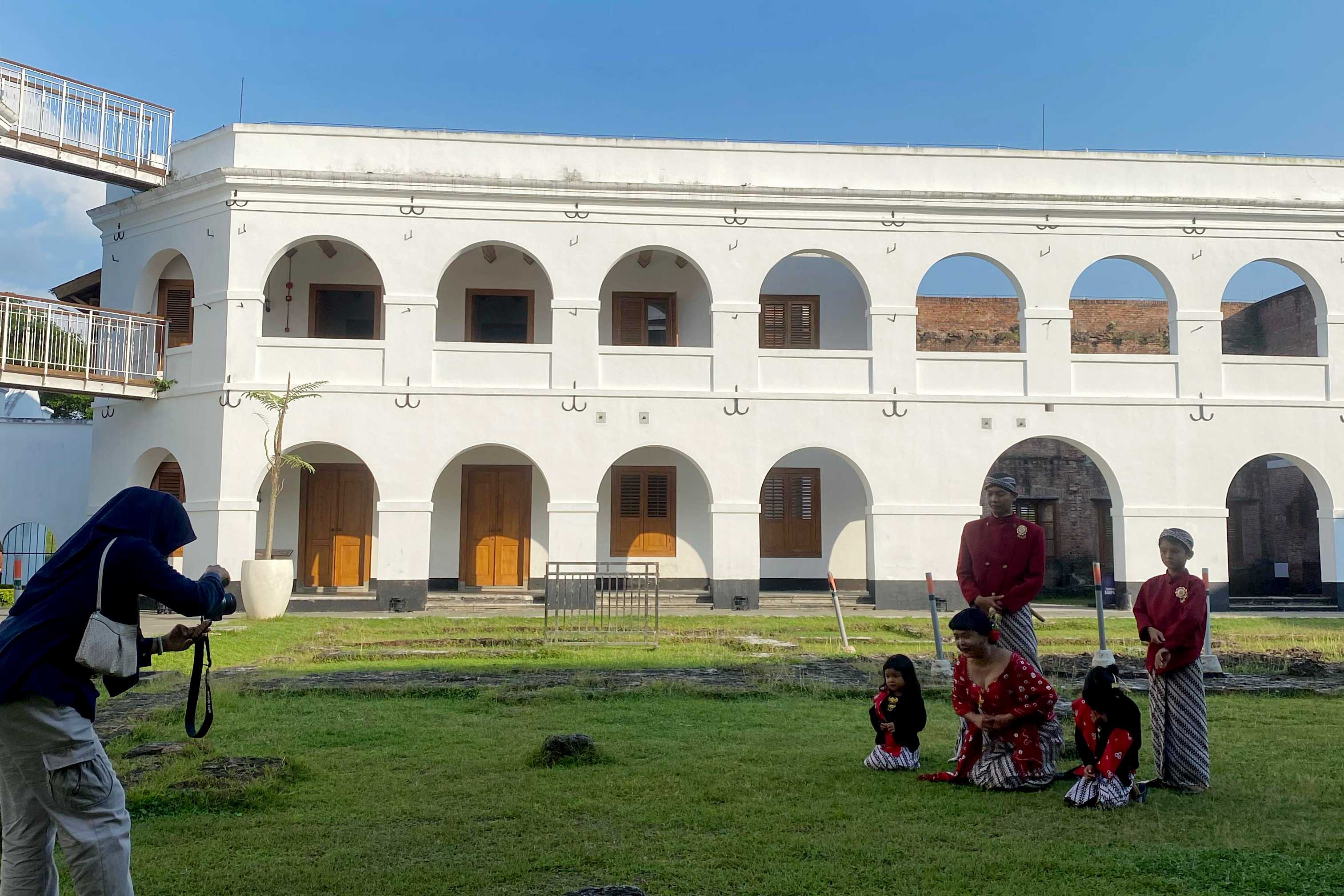 Satu keluarga memakai pakaian adat&nbsp;dan berfoto dengan latar Benteng Pendem.