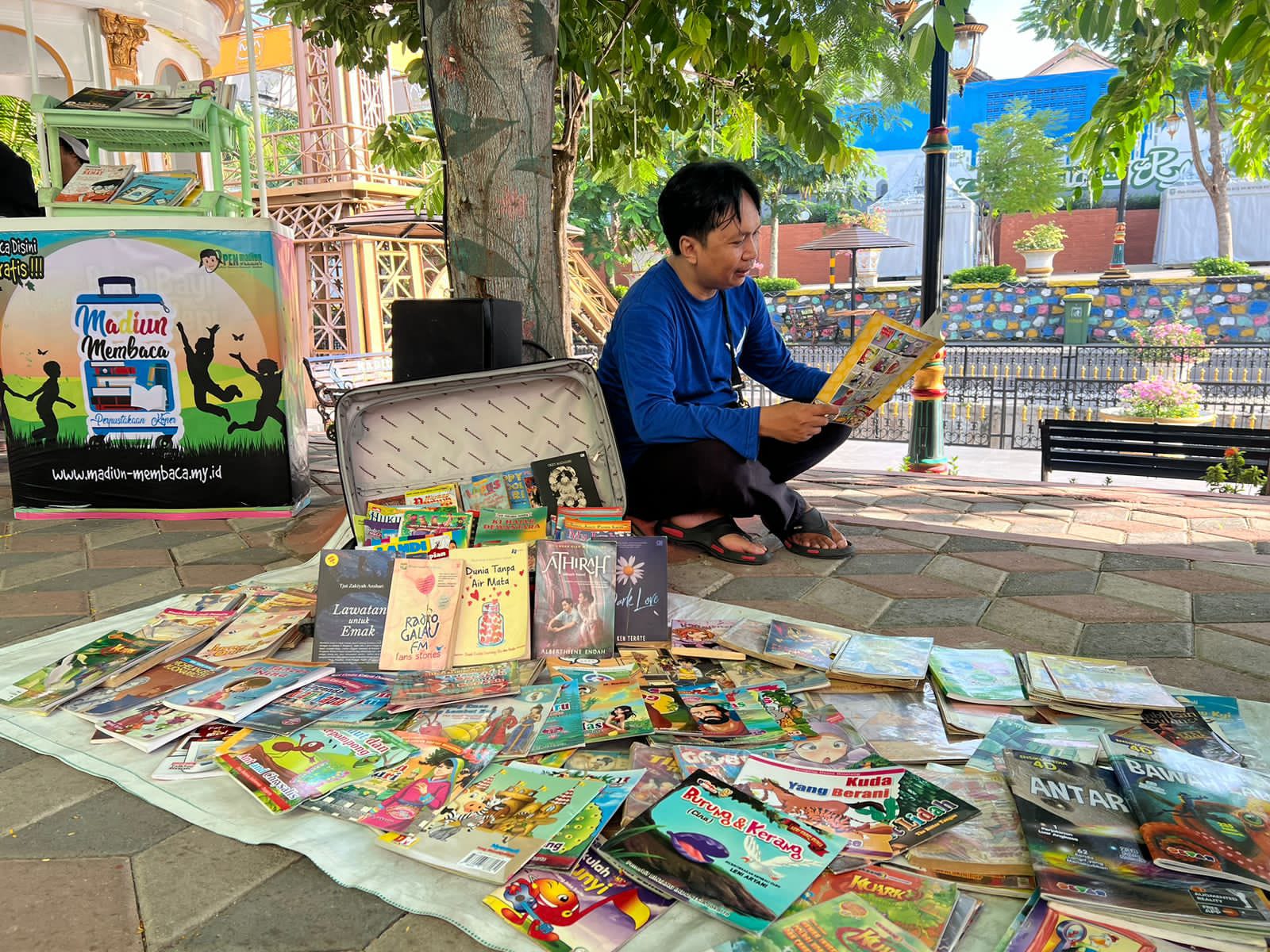 Yosep Rusfendi rutin membawa koper berisi ratusan buku ke ruang publik Madiun. FOTO: ISTIMEWA