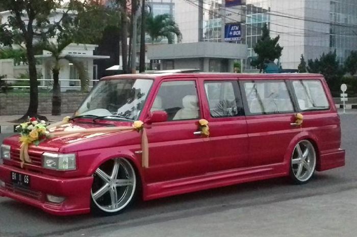Kijang Grand Extra warna marun dipasangi bunga plastik, jadi mobil pengantin low budget nan meriah.