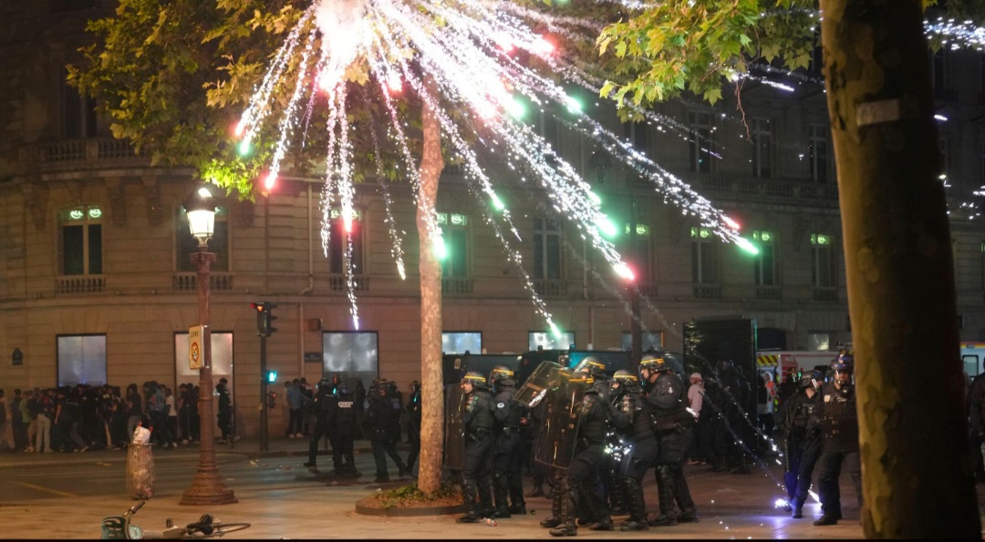 Kembang api meledak di atas polisi antihuru-hara di Champs-Elysees.