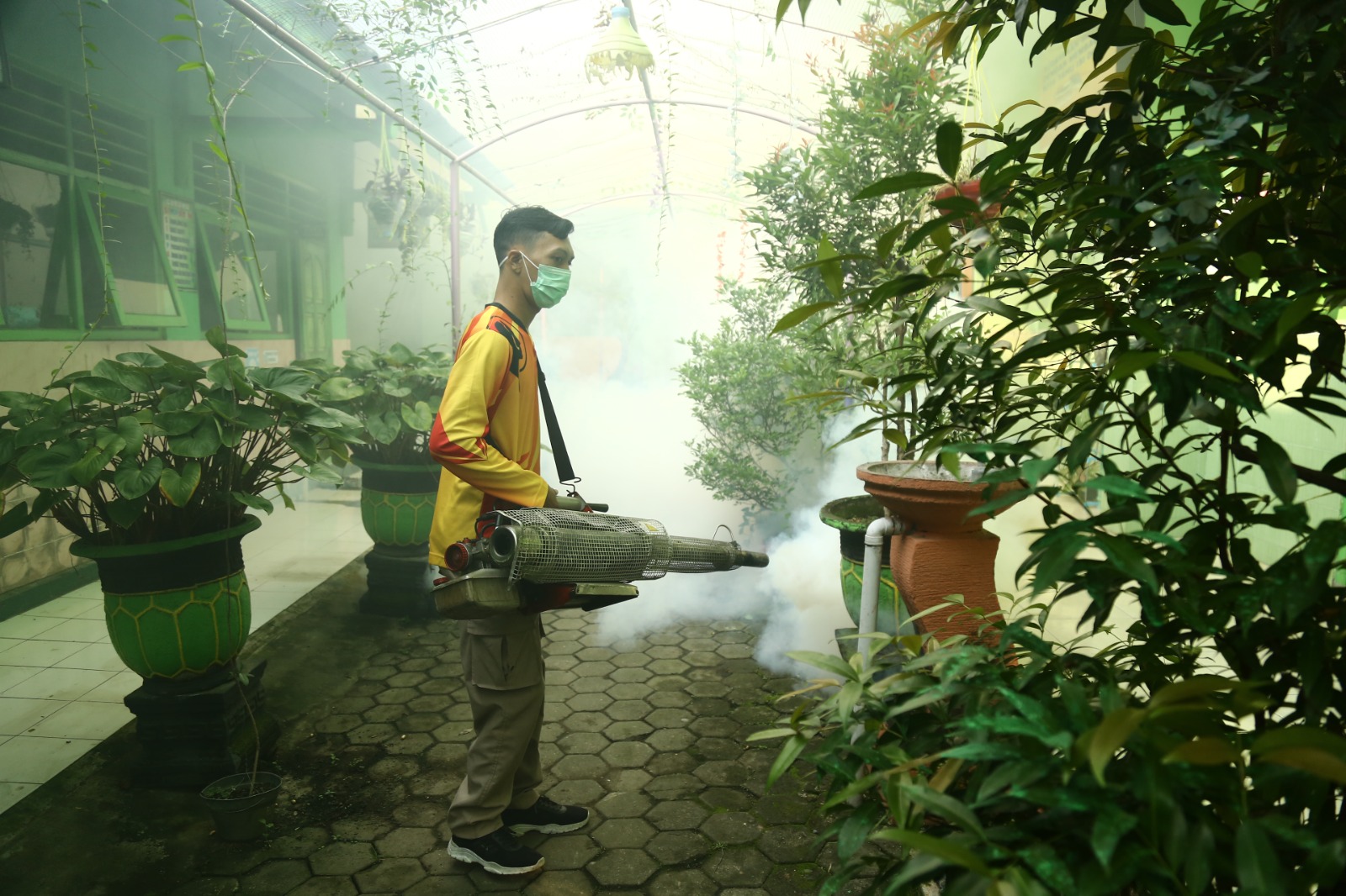 Petugas Puskesmas Ngegong menyemprotkan fogging di lingkungan SDN 02 Madiun Lor untuk memberantas nyamuk DBD, Kamis (12/6). BAGAS BIMANTARA/JAWA POS RADAR MADIUN
