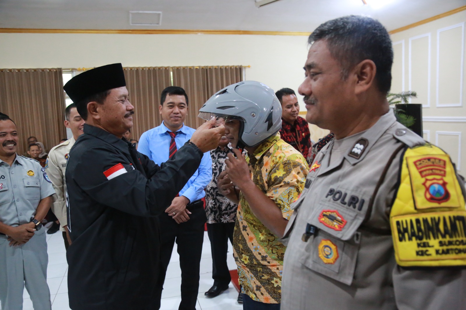Wali Kota Maidi memasangkan helm kepada tiga pilar yang ikut membantu mengedukasi kepada WP agar tidak telat membayar opsen pajak. FOTO: BAGAS BIMANTARA/RADAR MADIUN