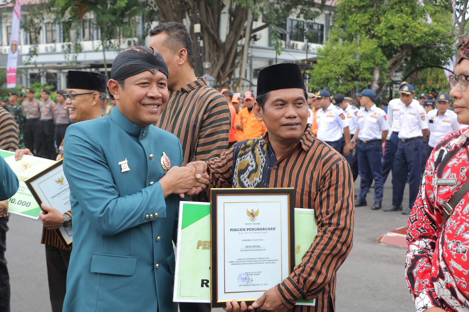 TERIMA PENGHARGAAN: Wabup Ngawi Dwi Rianto Jatmiko menyerahkan piagam penghargaan pembangunan bidang kesehatan kepada Kelapa Desa Begal Yusuf Setyono.