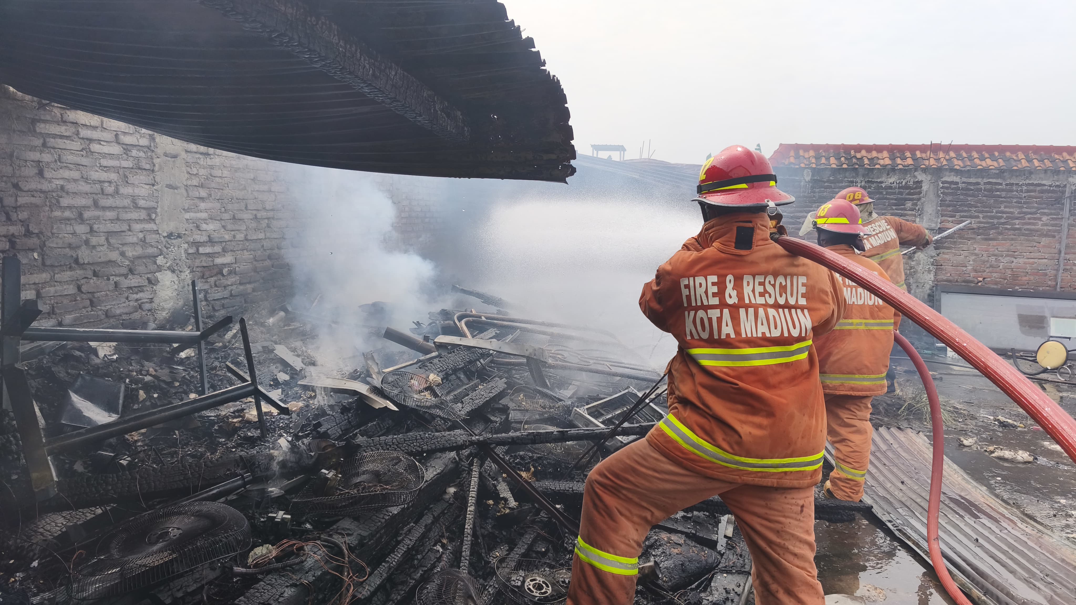 Petugas Satpol PP dan Damkar Kota Madiun memadamkan api yang sempat muncul dari gudang Ayam Geprek dr. R di Jalan Ciliwung, Sabtu (12/7). FOTO: SATPOL PP DAN DAMKAR KOTA MADIUN