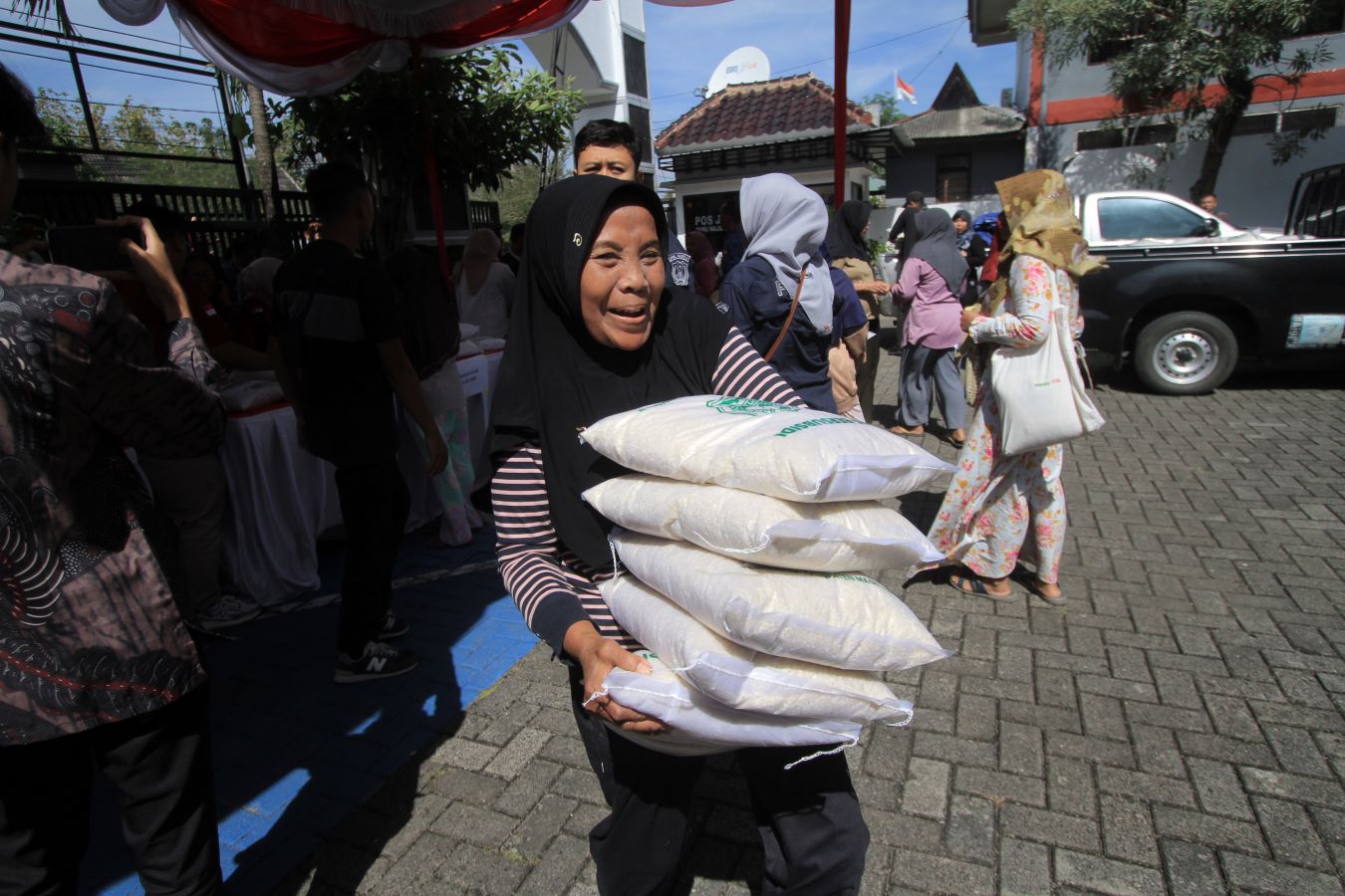 GEMBIRA: Seorang ibu-ibu gembira usai membeli beras dengan harga murah di bazar murah, Kamis 17 Juli 2025.